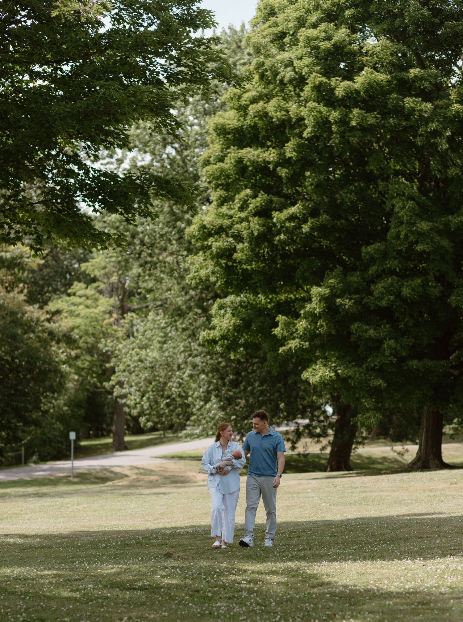 Two people walking together on a grassy hill in a peaceful park setting on a sunny summer day.