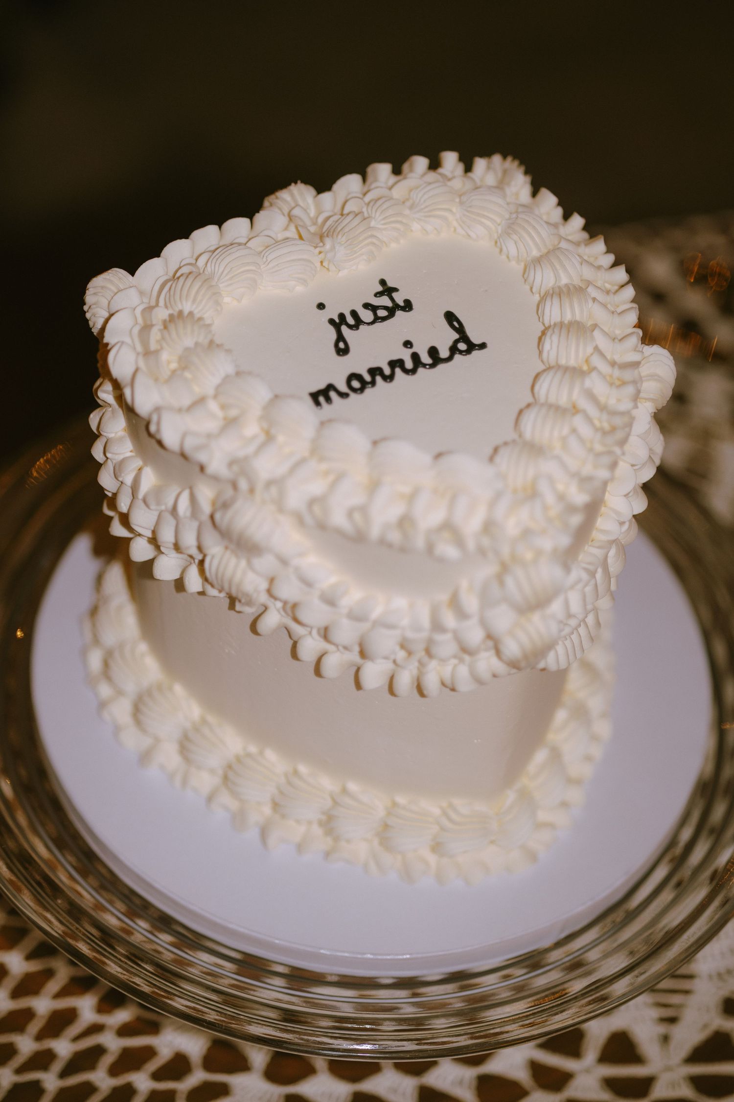 A heart-shaped white wedding cake with piped frosting decorations and 