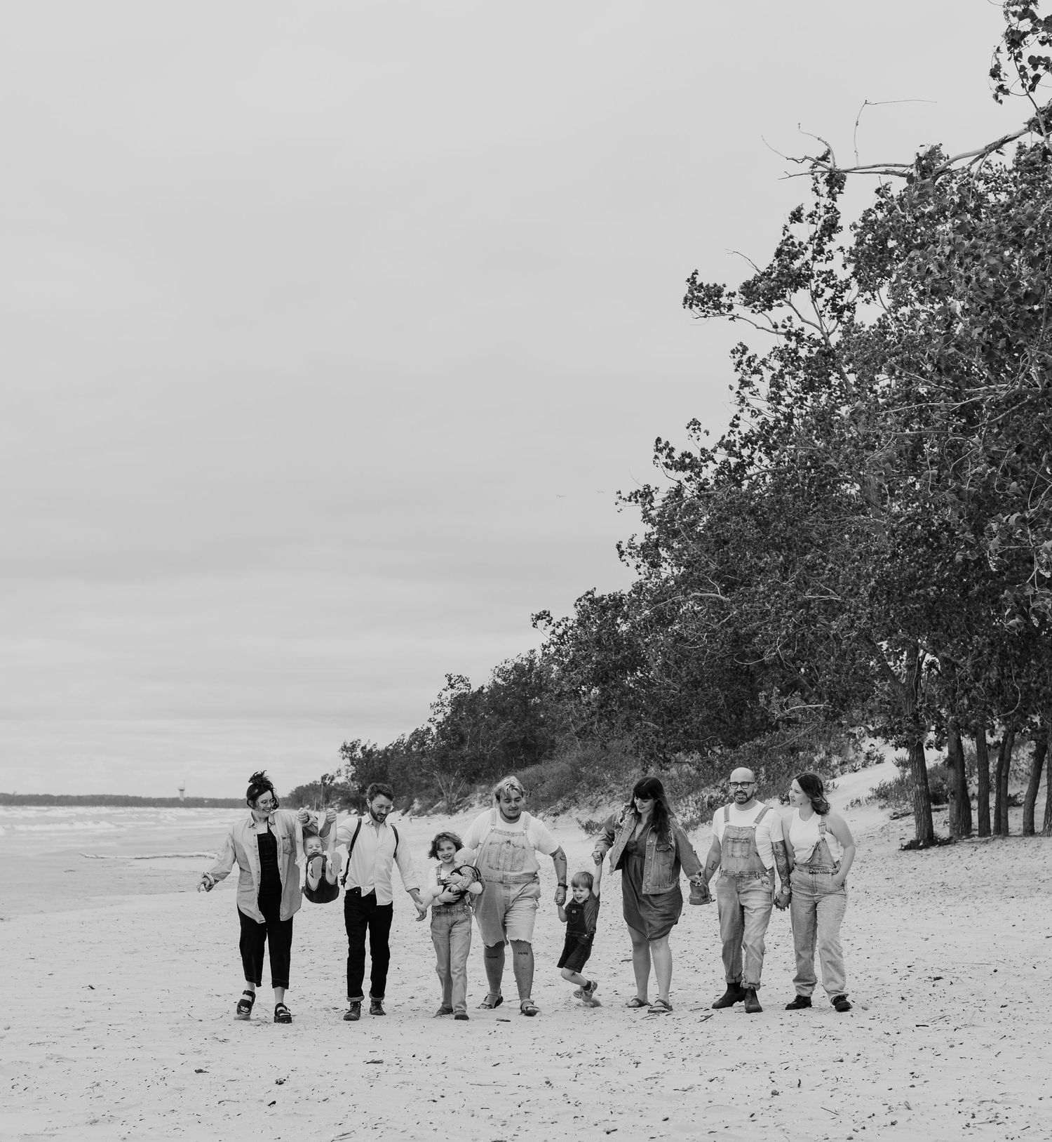 Group walking together along a beach shoreline in black and white photography.