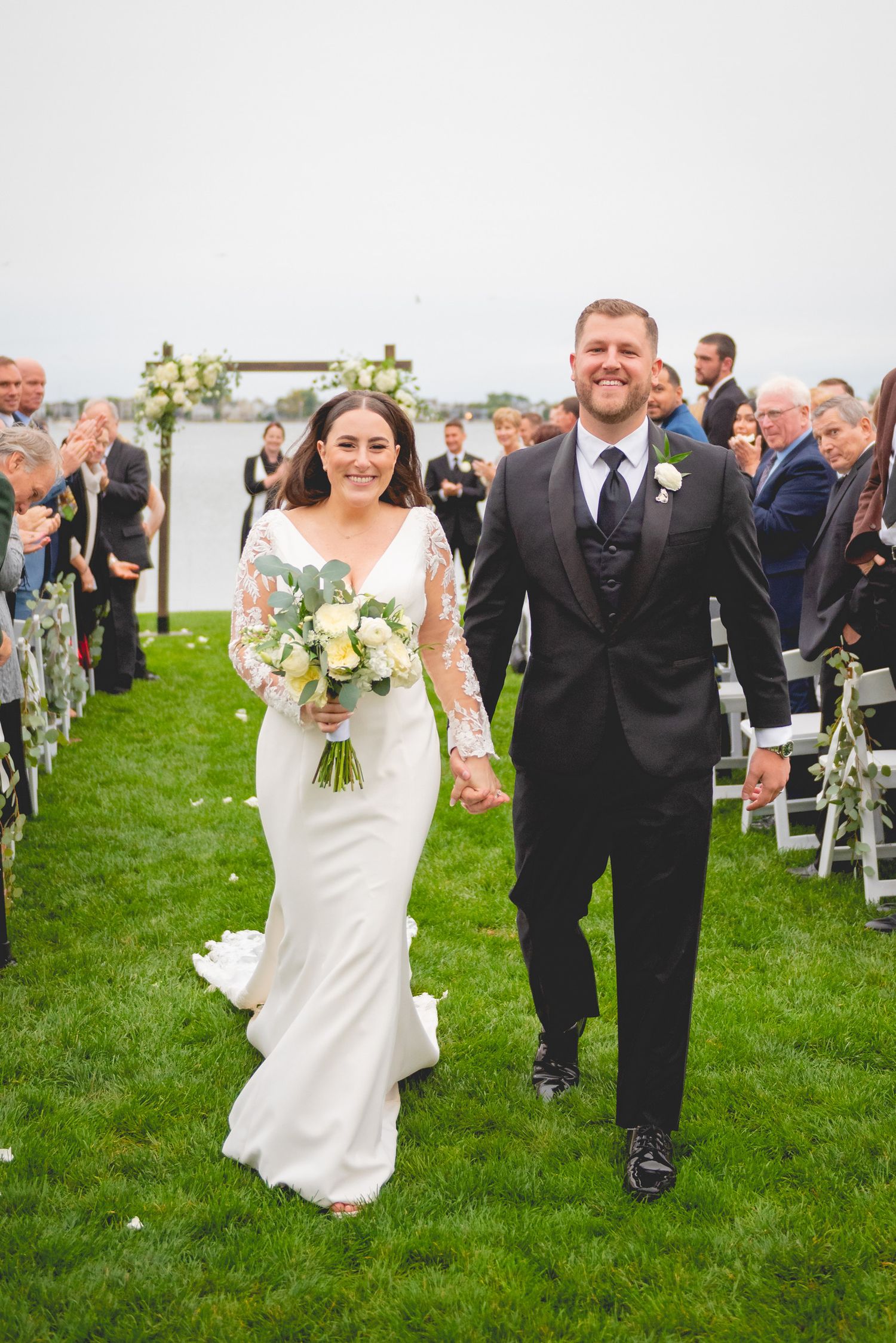 A joyful wedding ceremony on a grassy lawn with guests watching the celebration.