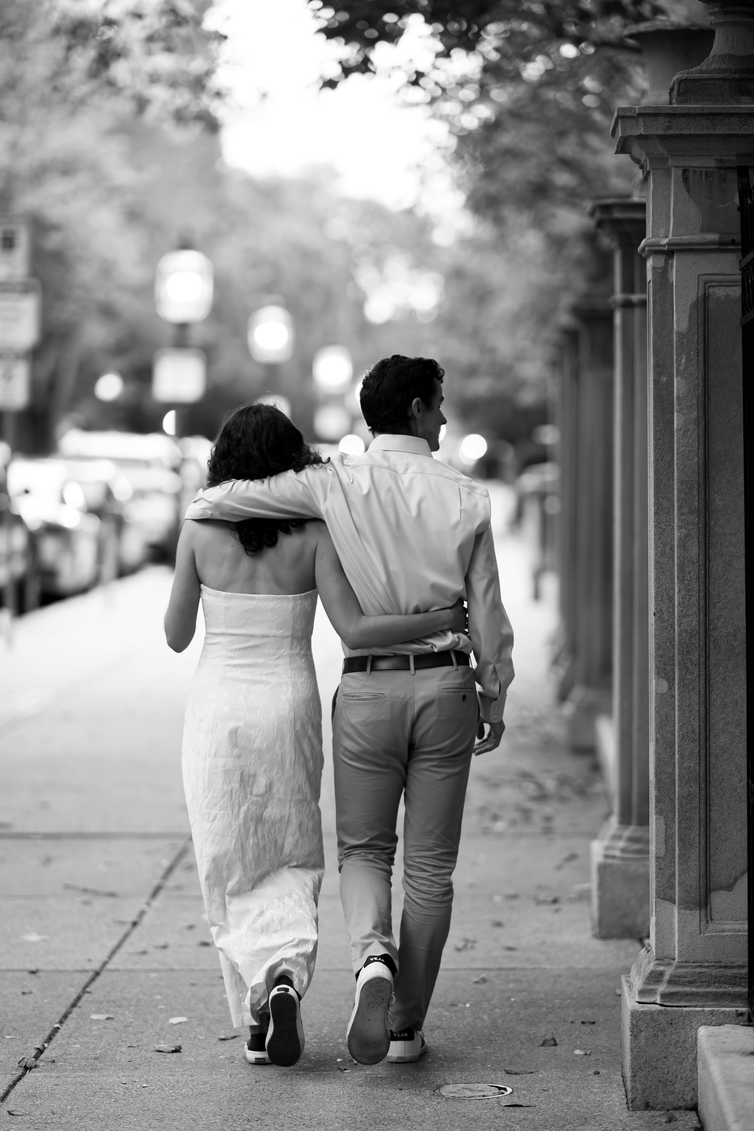 A couple walks arm in arm down a street in Boston, Massachusetts for their engagement photos.