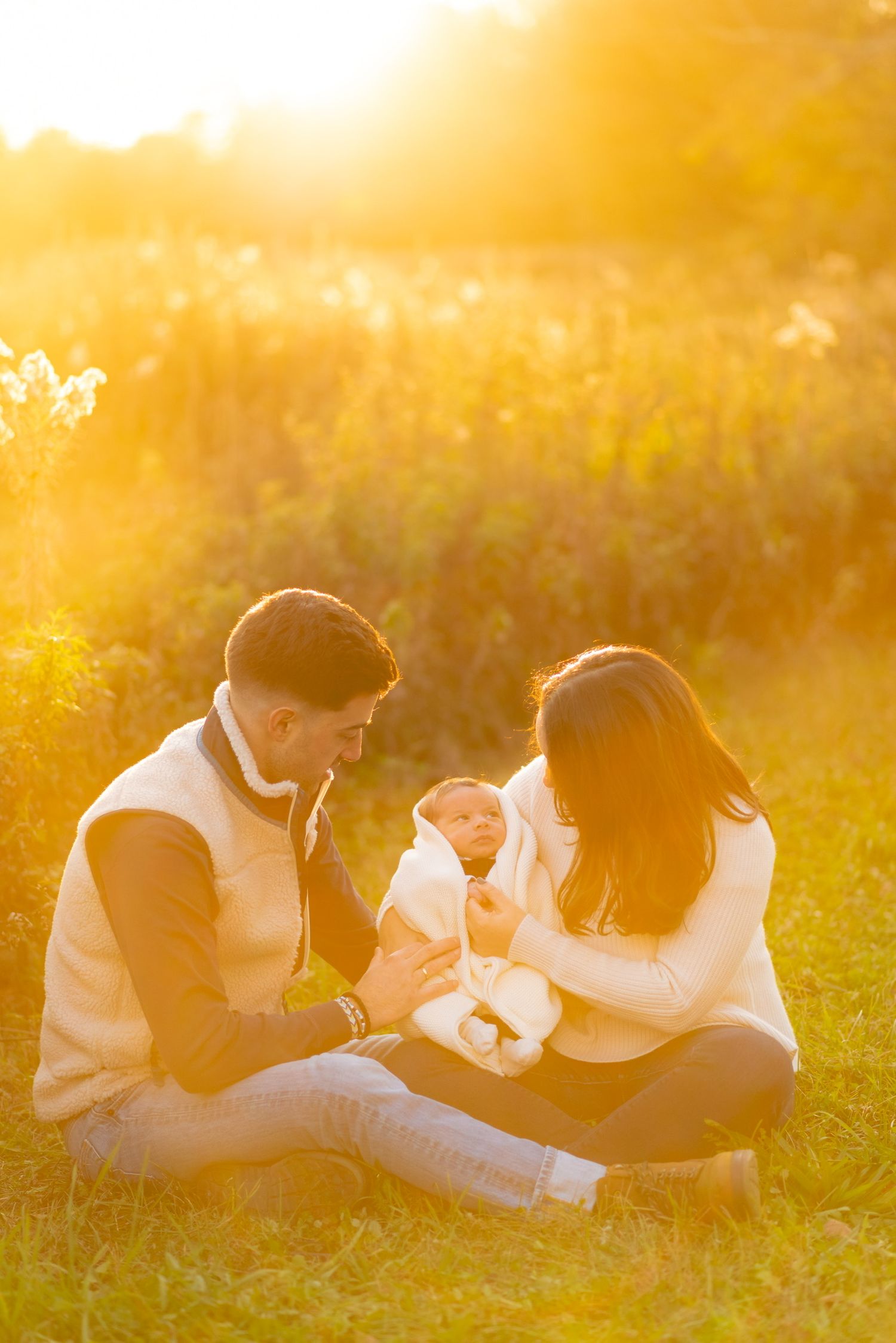 Family members lie together in golden sunlit grass creating a heartwarming scene.