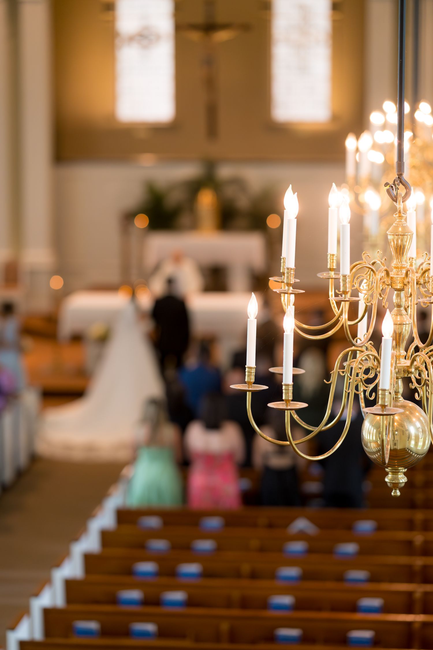 Church interior with glowing candelabras and wooden pews for a wedding ceremony.