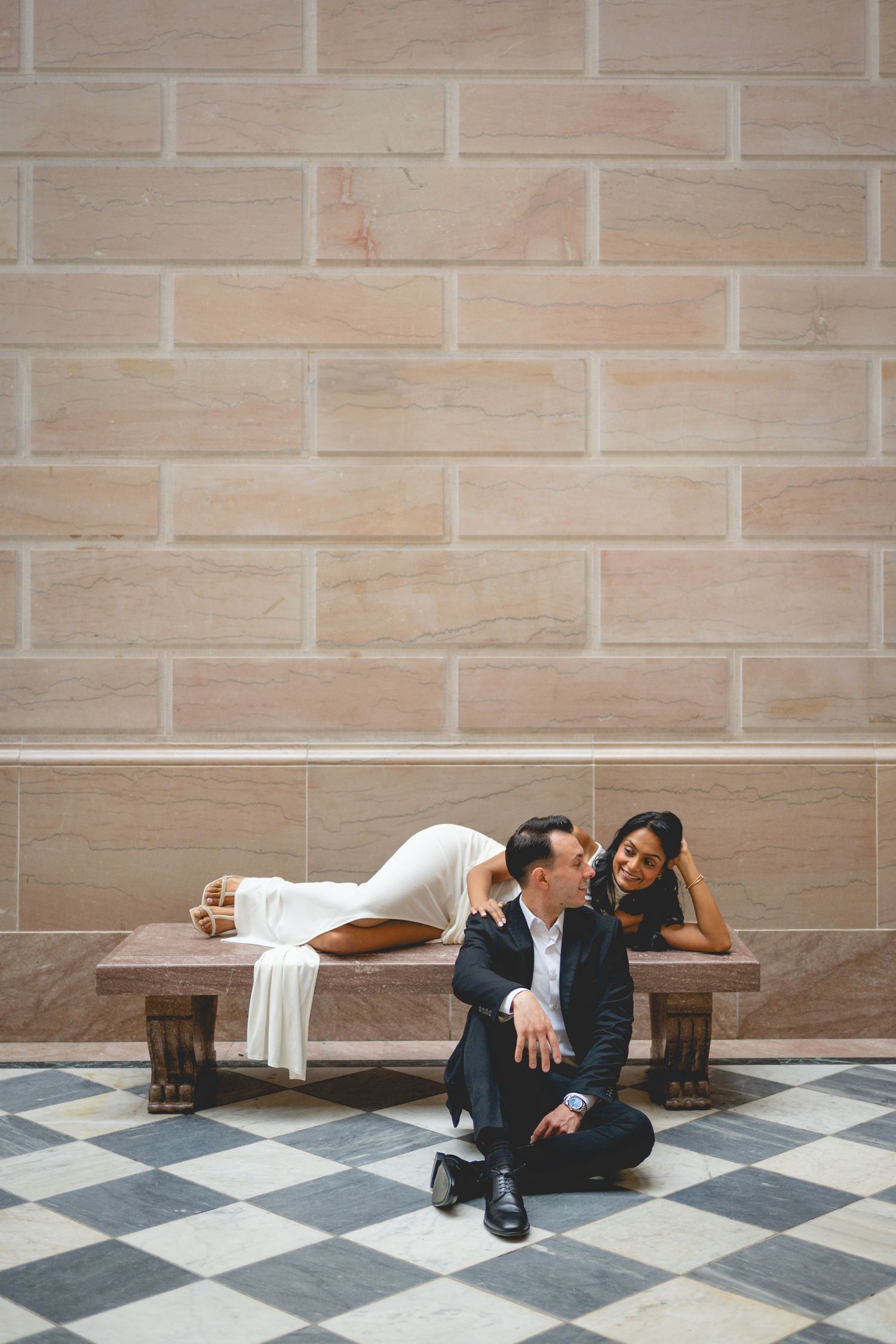 A couple creates artistic poses on a checkered floor in a formal setting at Hartford City Hall.