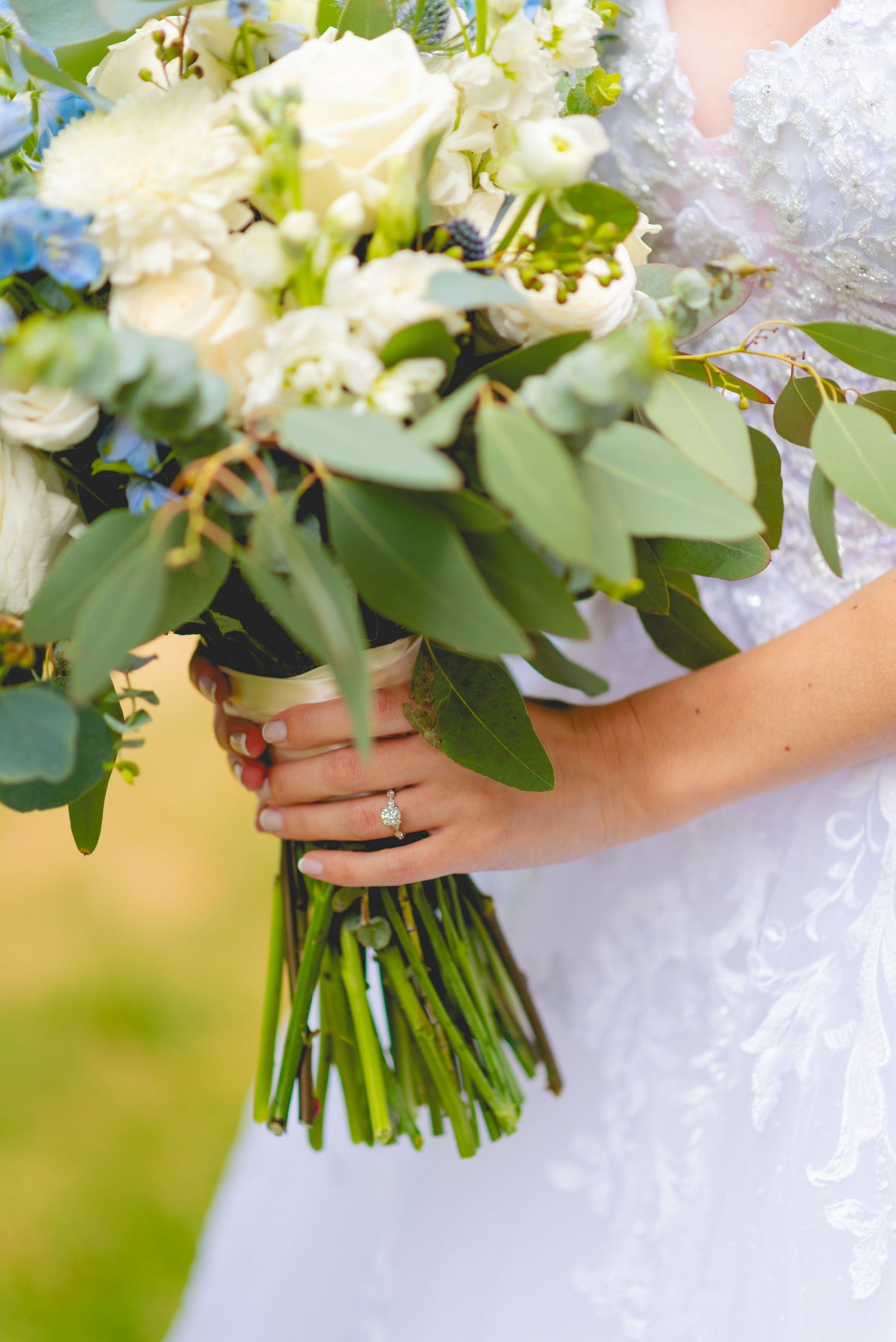 Fresh white and green wedding bouquet with delicate flowers and foliage tied with ribbon.