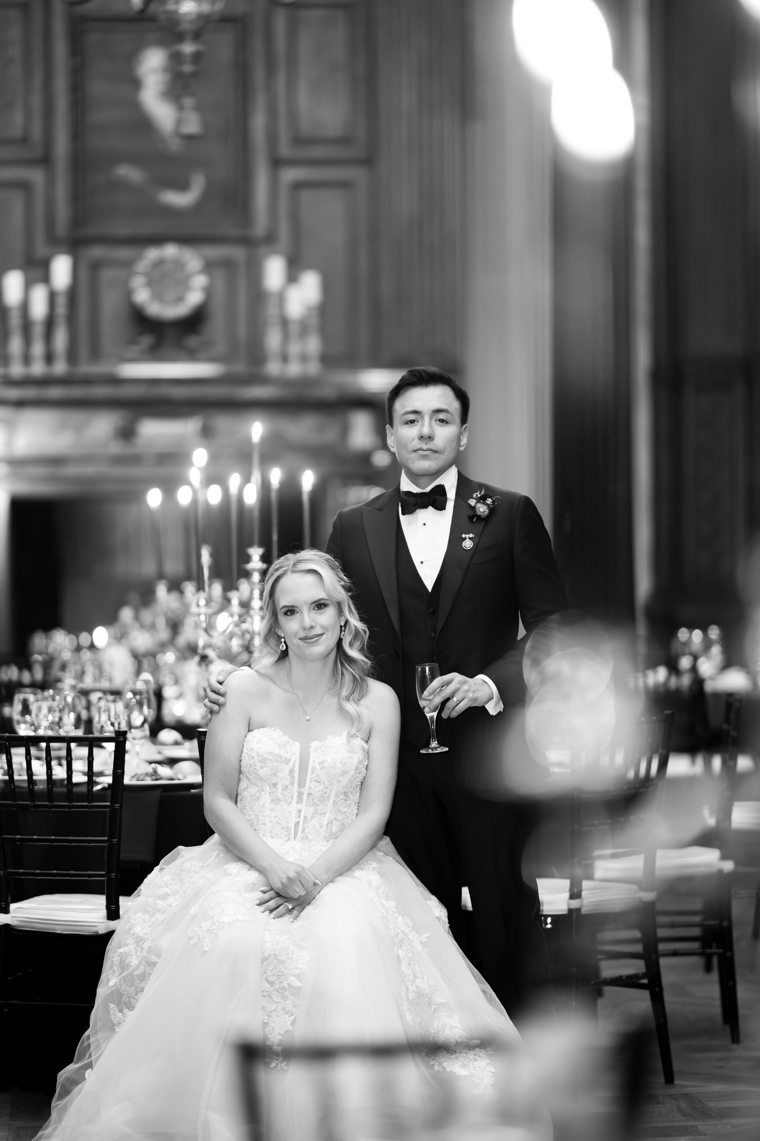 Elegant black and white wedding photos showing a bride in a ballgown and groom in tuxedo at a formal reception venue.