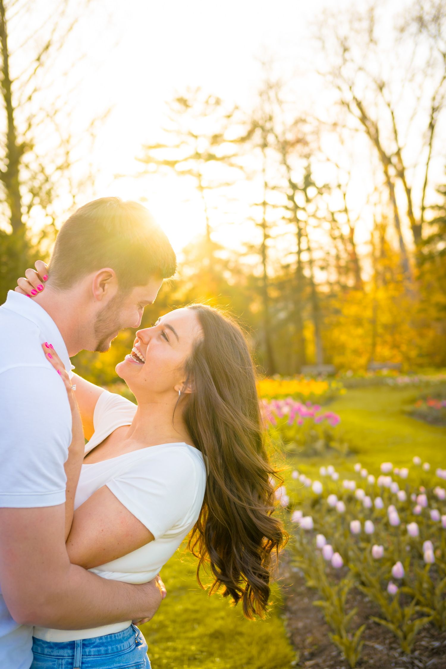 Romantic couple embraces in a spring garden with tulips during golden hour sunset.