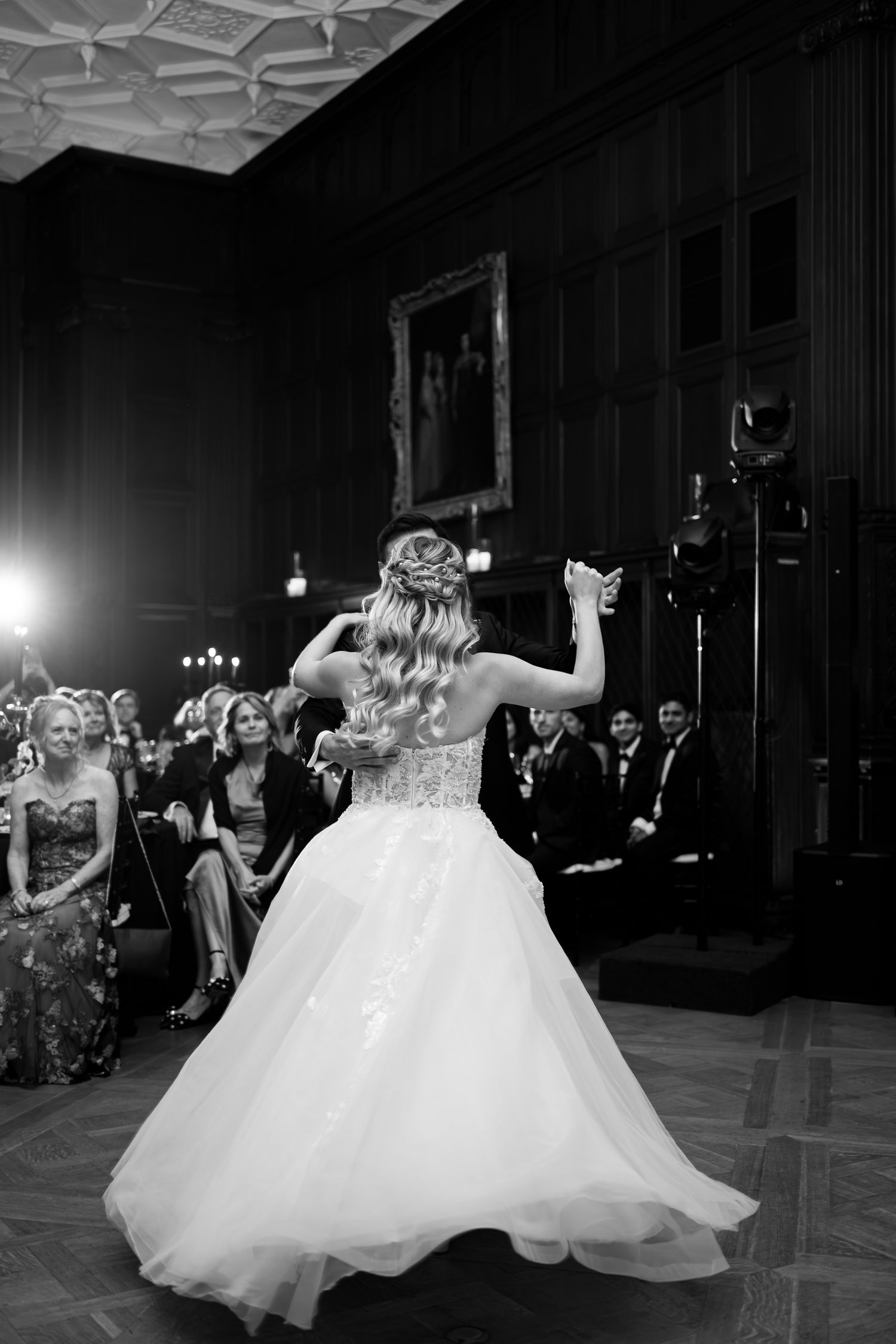 A bride in a voluminous white gown twirls on the dance floor during a wedding reception.