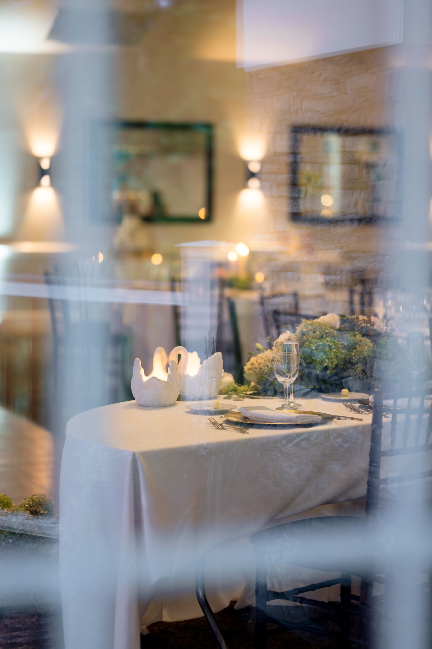 Elegant restaurant interior with white tablecloths and soft wall sconces creating an intimate fine dining atmosphere.