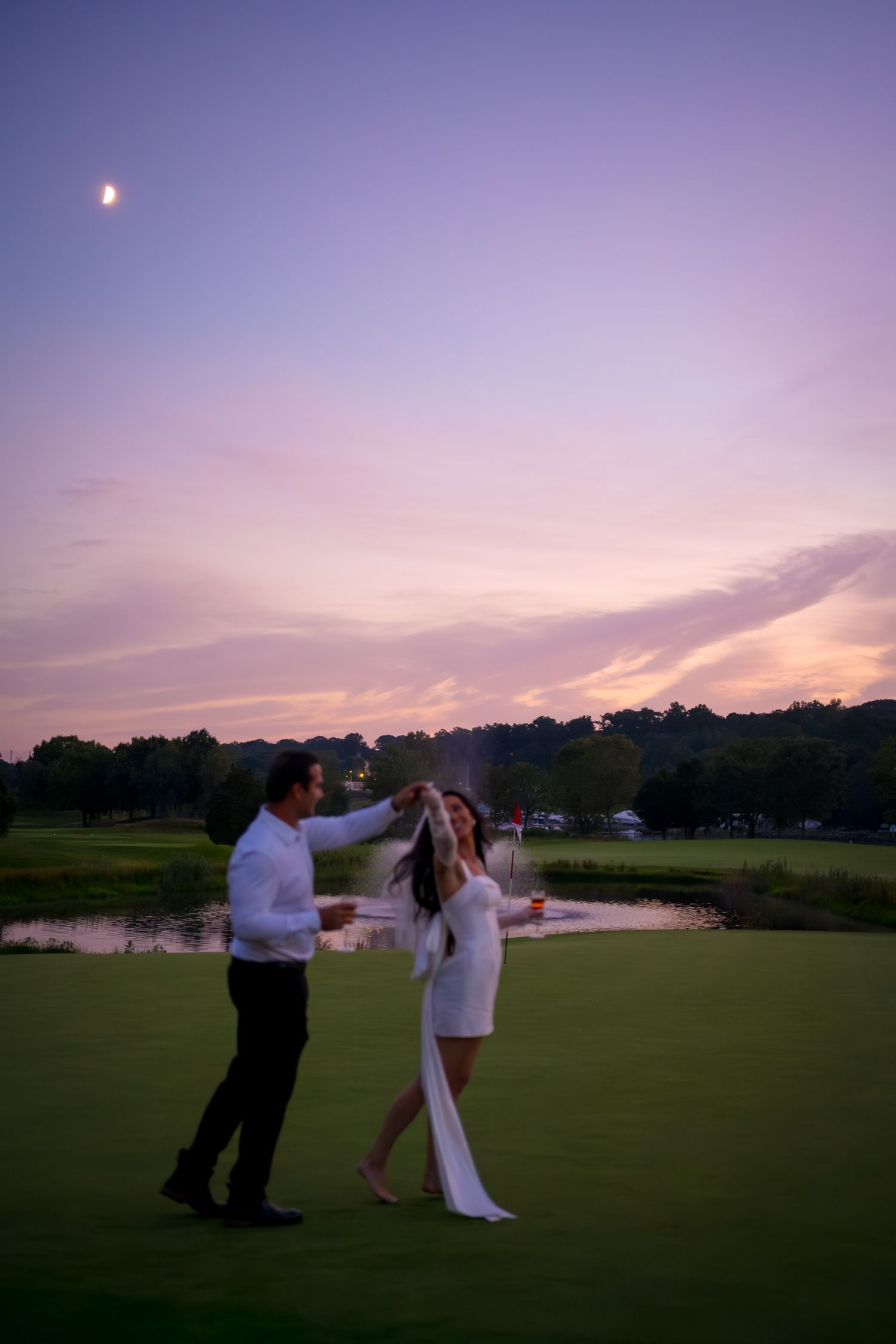 Silhouettes dance on a golf course at sunset with purple sky.