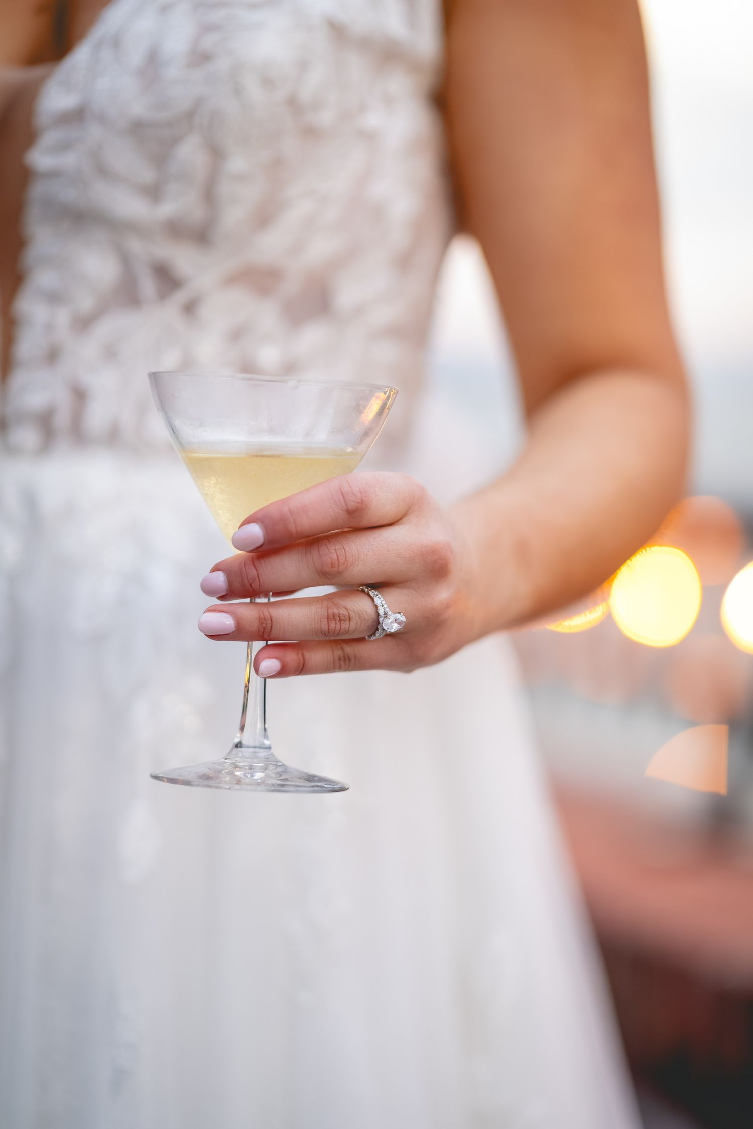 Close-up of hands holding champagne glass with wedding ring detail.