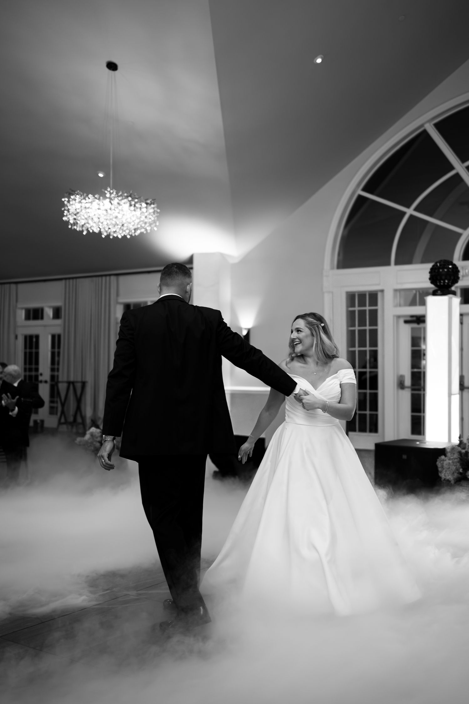 A couple dances in fog during their first dance at an elegant wedding reception.