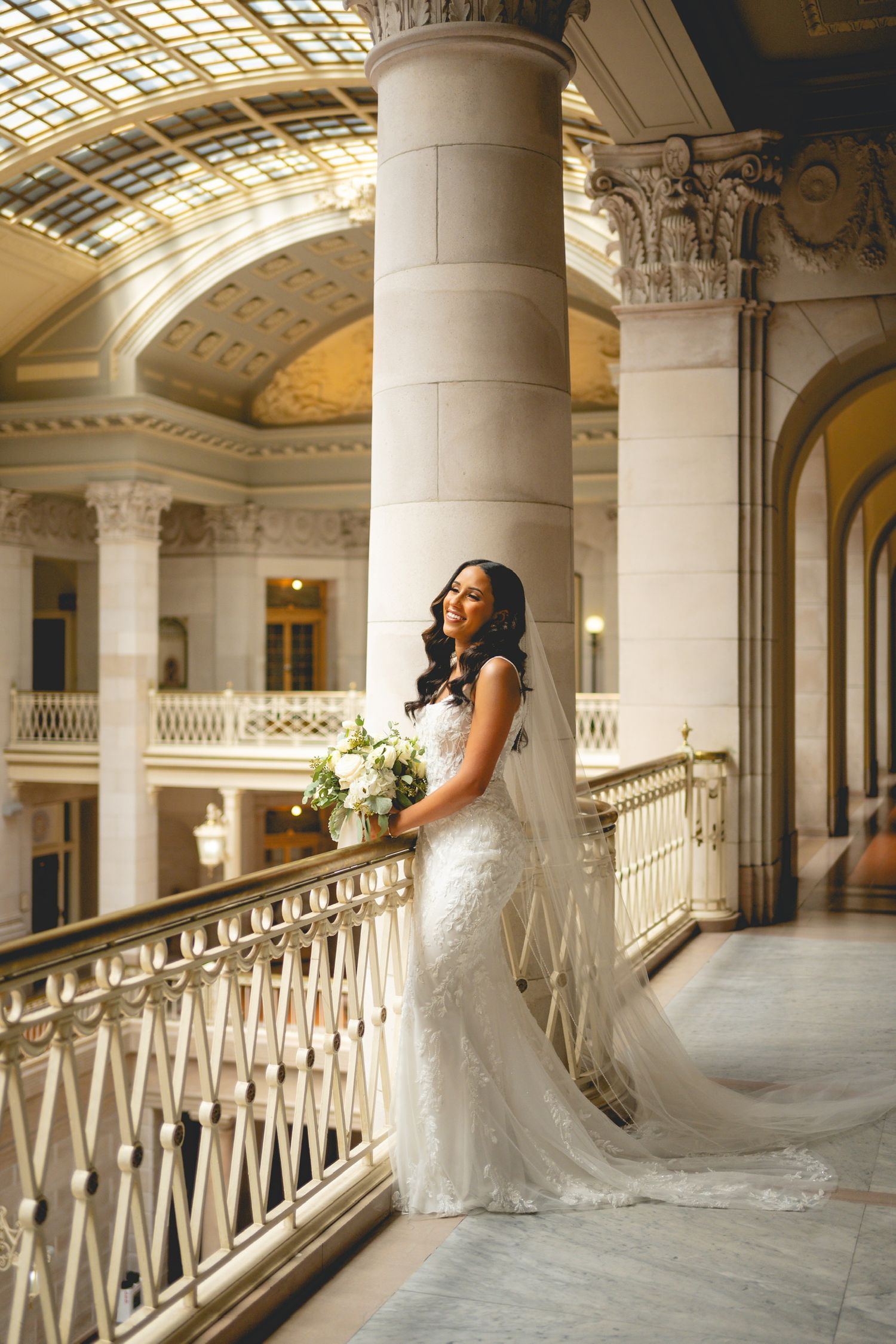 Elegant bridal portraits in columned gallery with natural lighting.