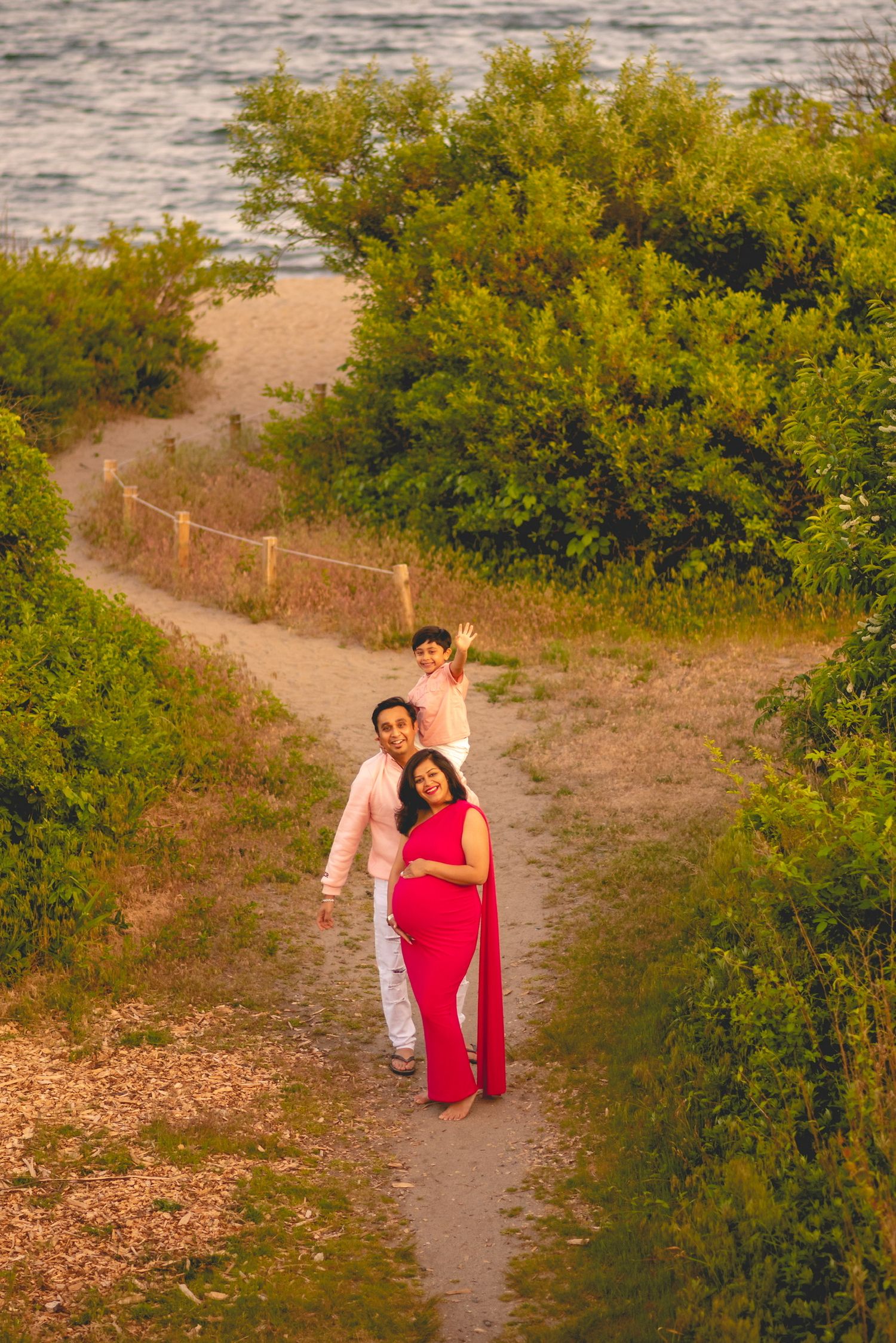 A couple walking along a nature path with blooming yellow bushes at sunset.