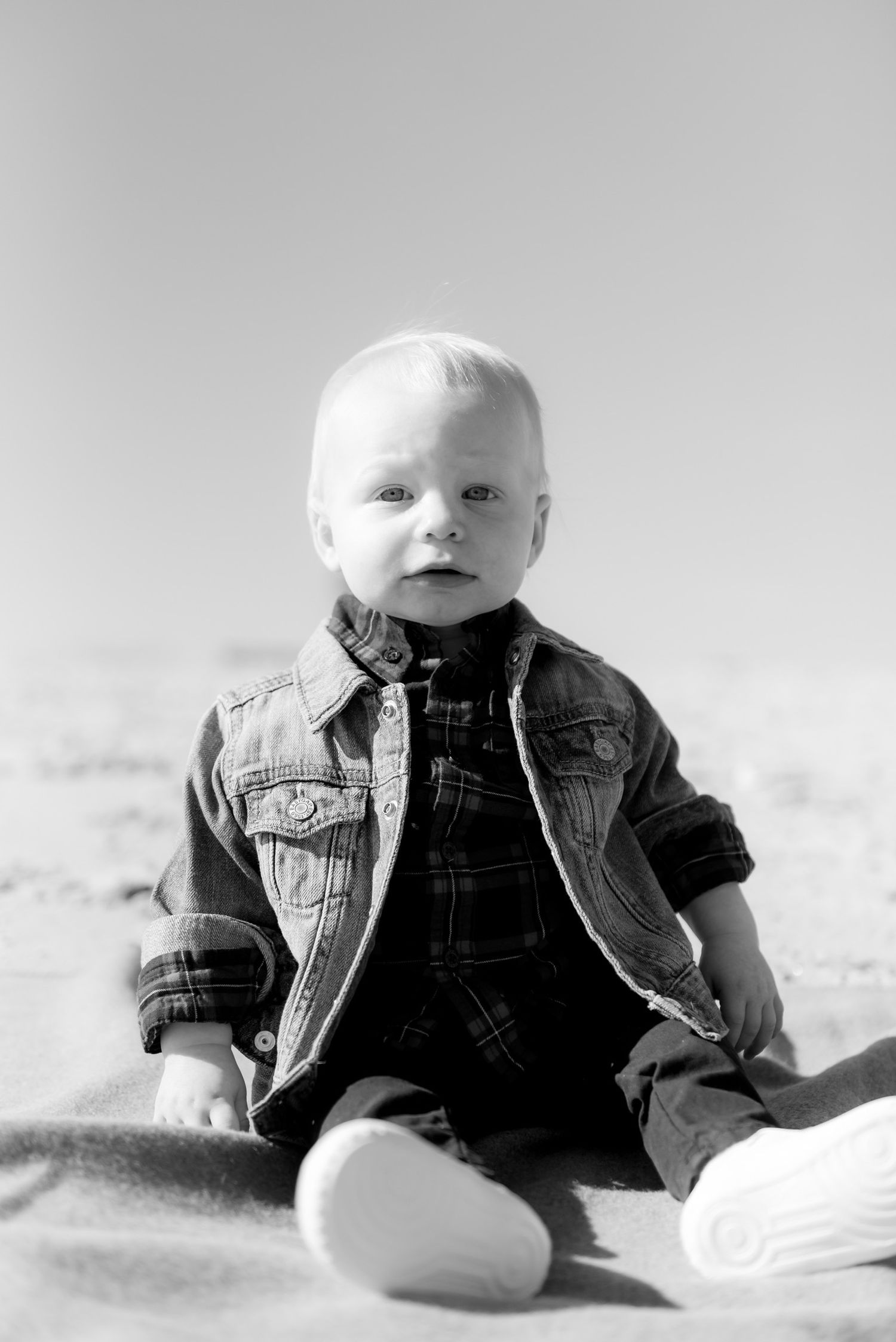 Baby in denim overalls lying on white background in black and white photography.