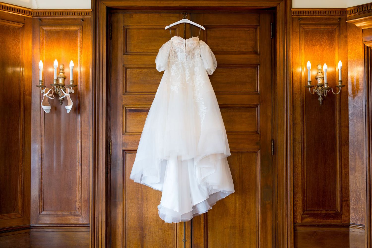 White wedding dress and accessories hanging in a wood-paneled room at Reid Castle in New York.