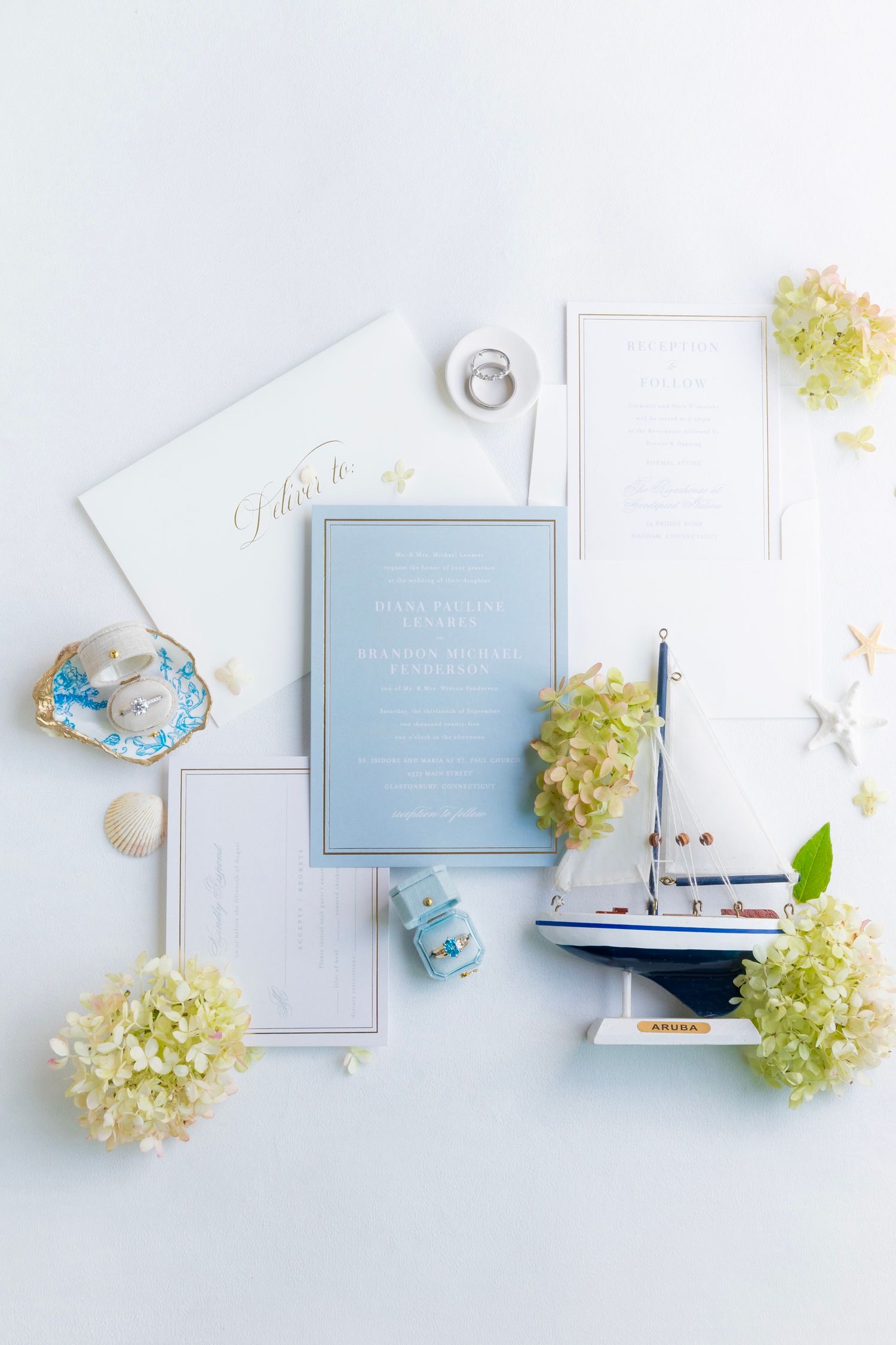 Elegant wedding invitation suite with pale blue accents and white hydrangea blooms on light background.