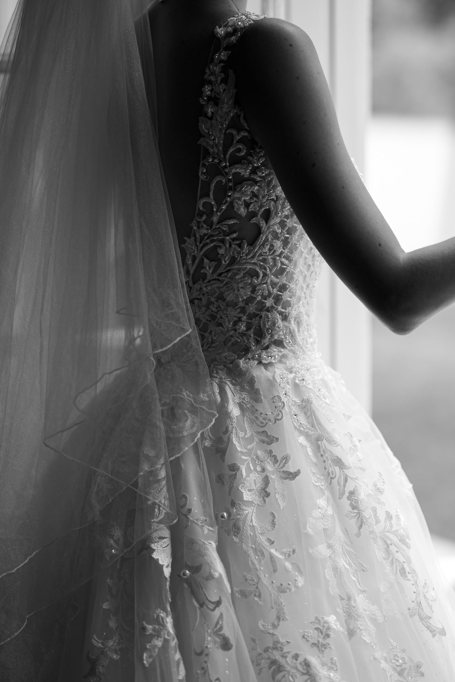 Close-up detail of intricate lace patterns on a white wedding dress.