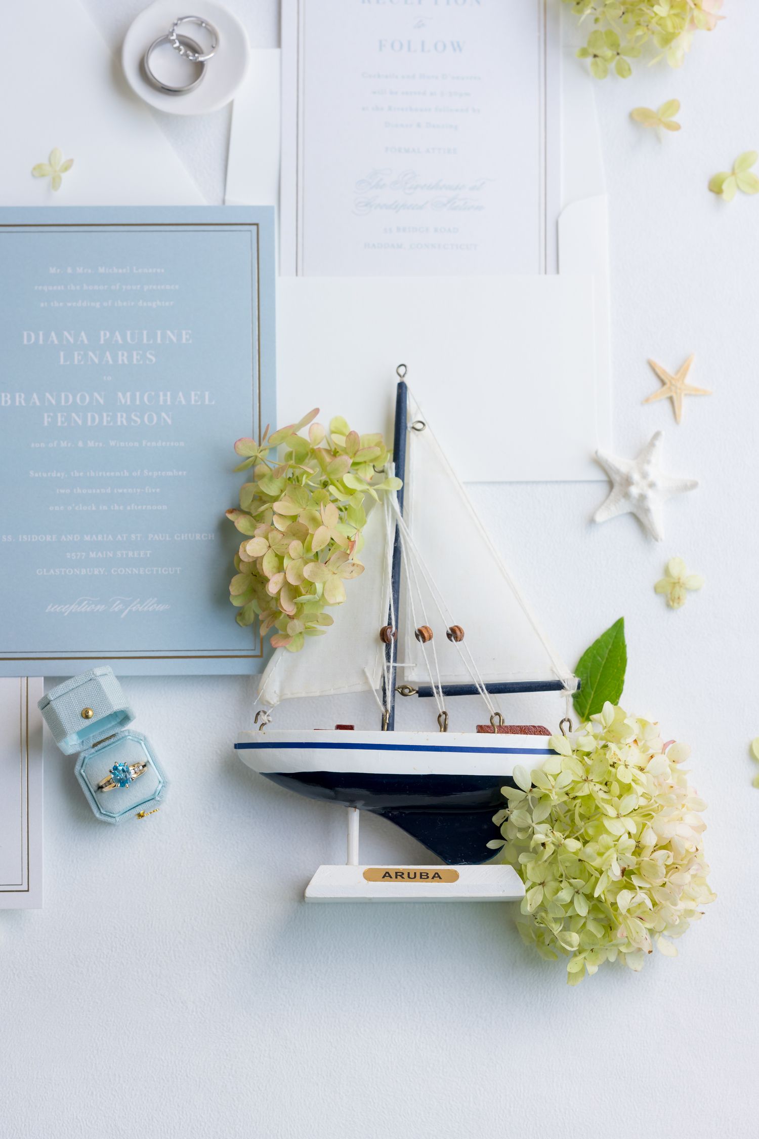 Wedding invitations with nautical decorations including model sailboats and hydrangea flowers on white background.