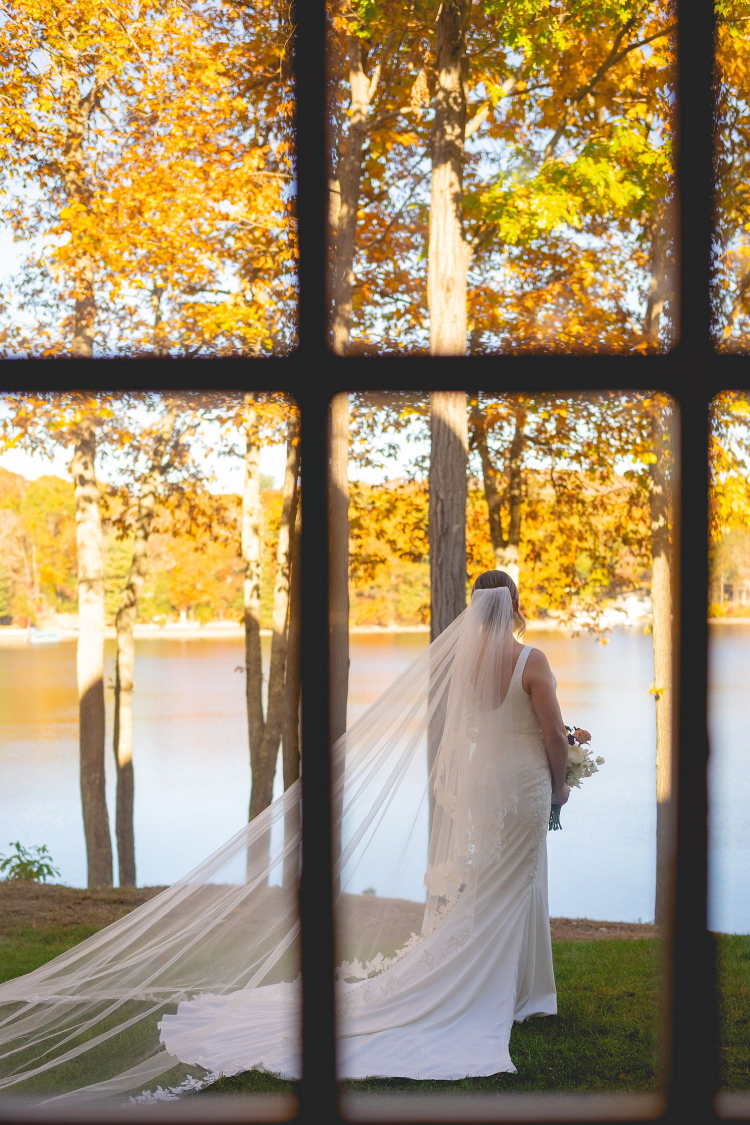 Wedding dress displayed outdoors among autumn trees with golden foliage.