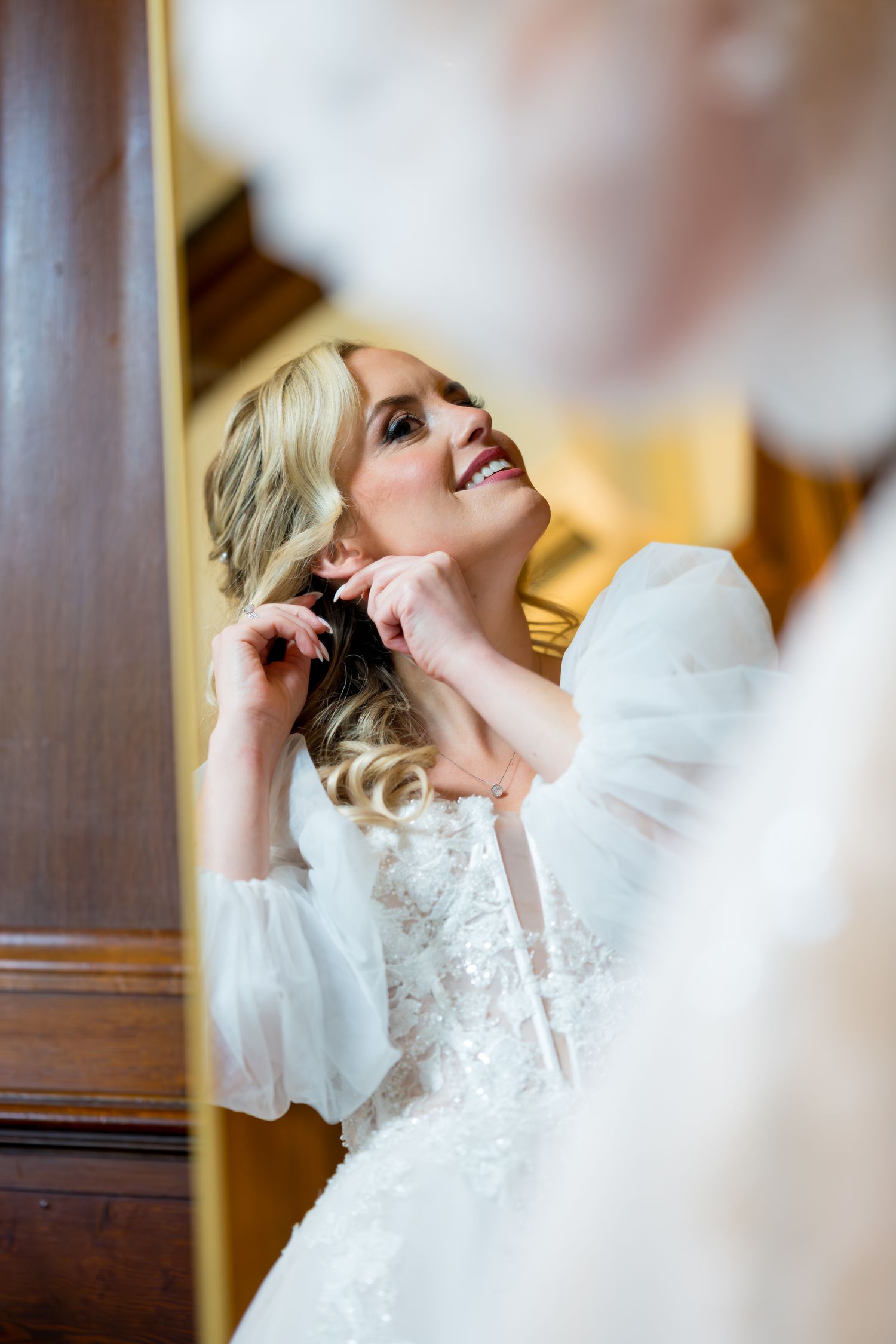 A bride in a white lace wedding dress laughs joyfully during a candid photo series.