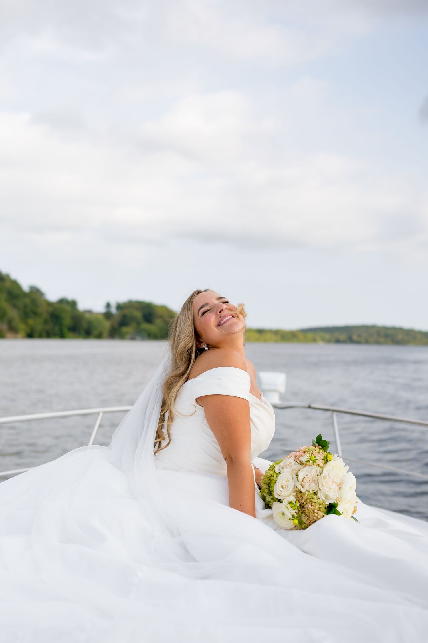 Wedding photography of a bride lounging on a boat with flowing white dress and bouquet.