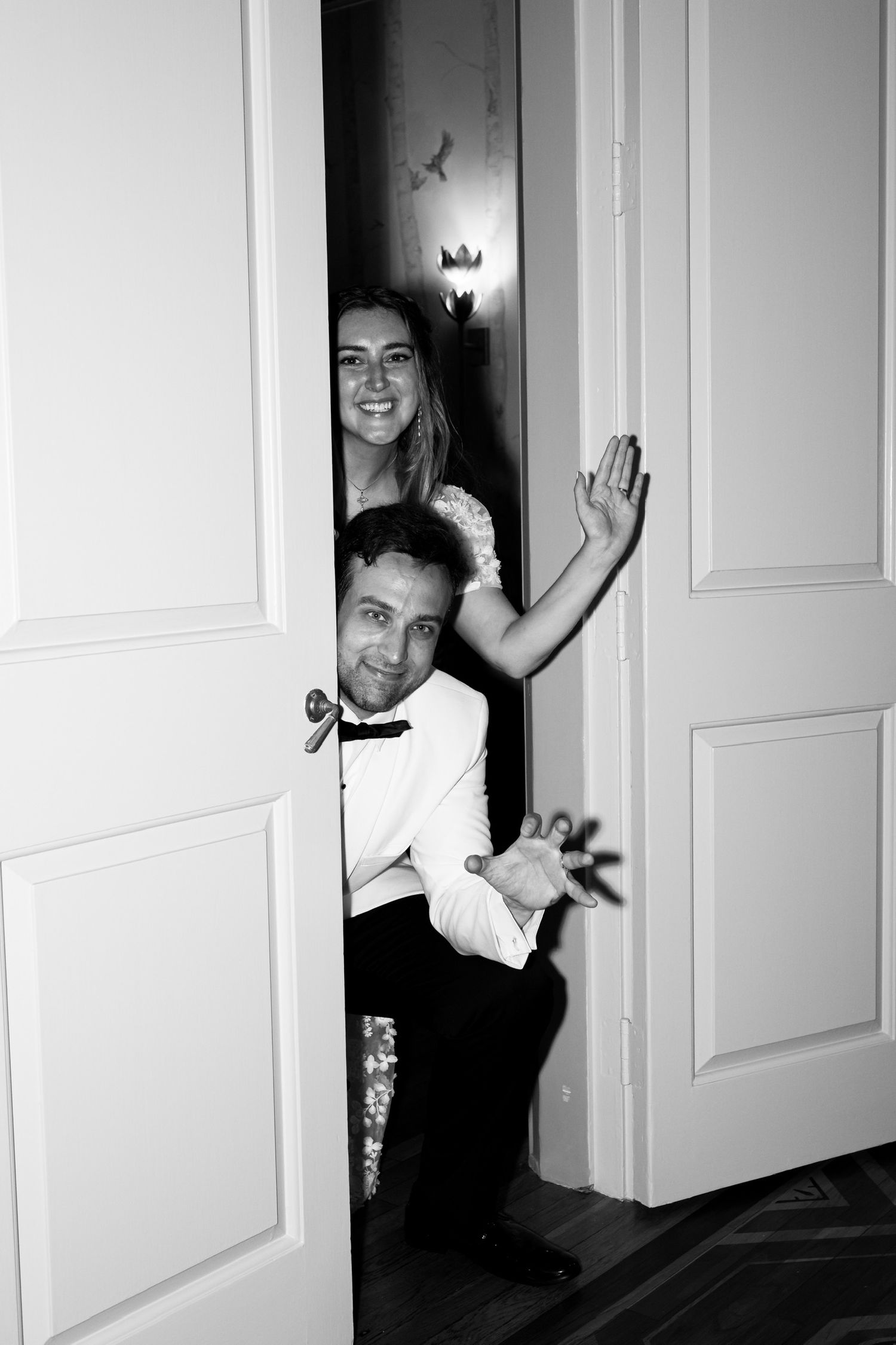 Playful black and white photo through doorway showing wedding party.
