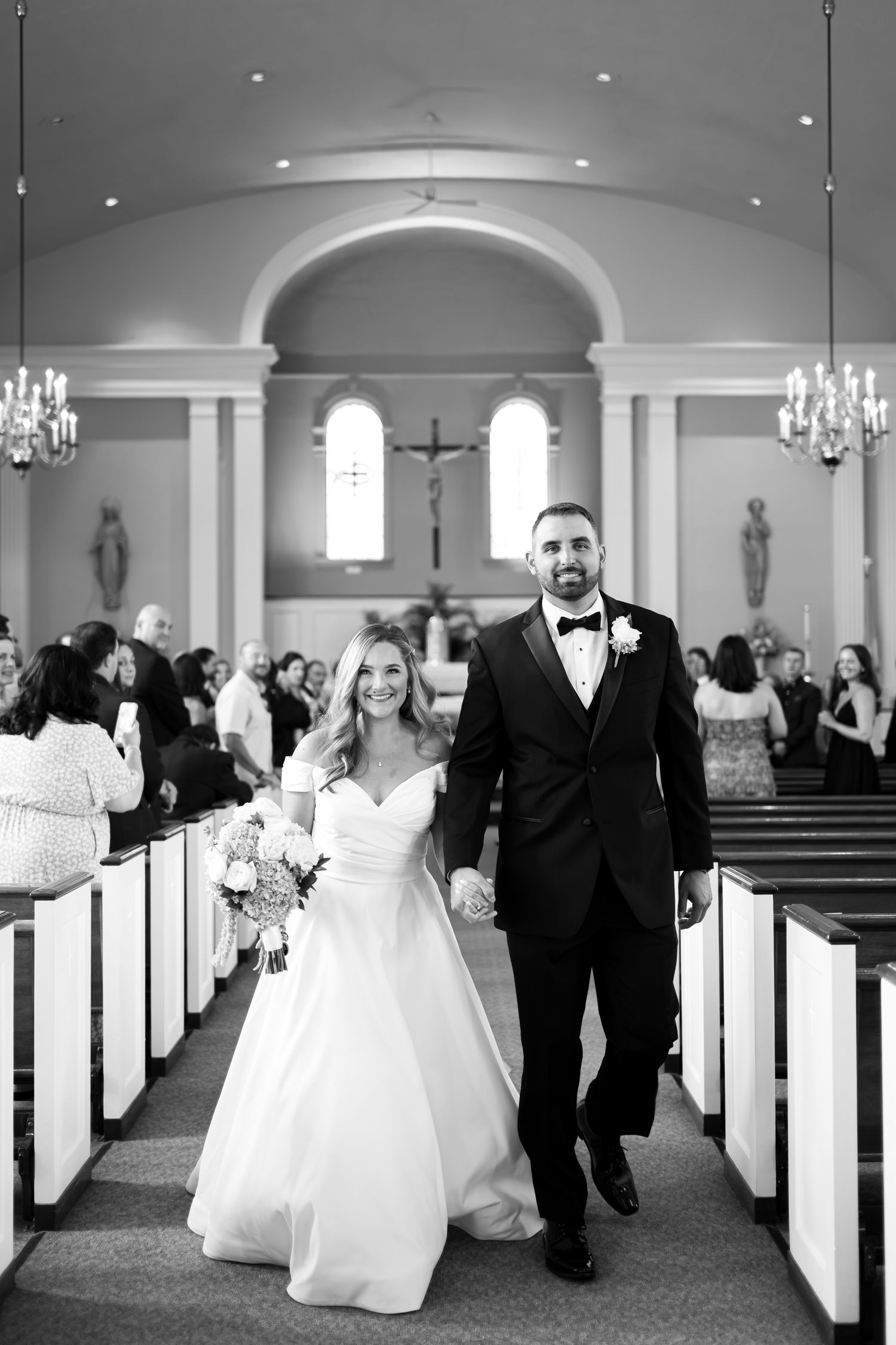 Wedding ceremony in a traditional church with white pews and arched ceilings.
