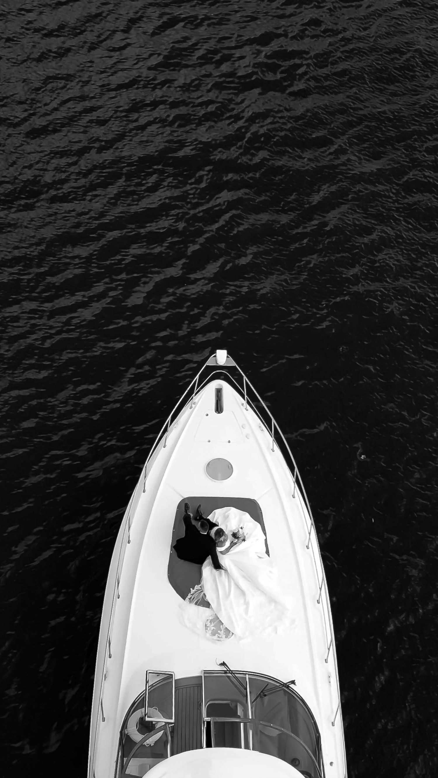 Aerial view of a white boat on dark water showing different angles of the vessel.