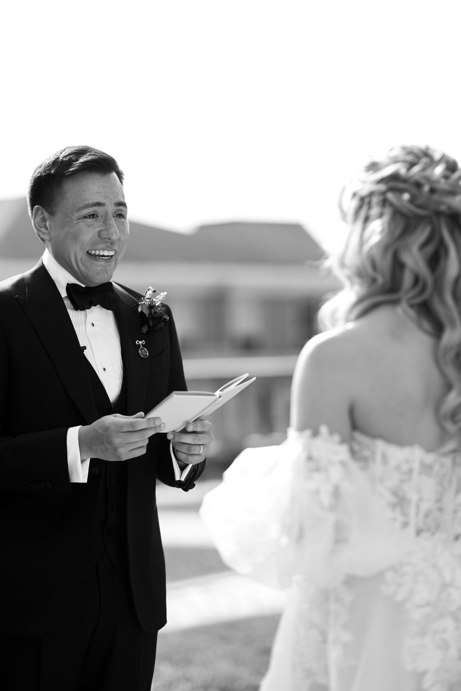 A touching first look moment between a bride and groom in formal wedding attire captured in black and white photography.