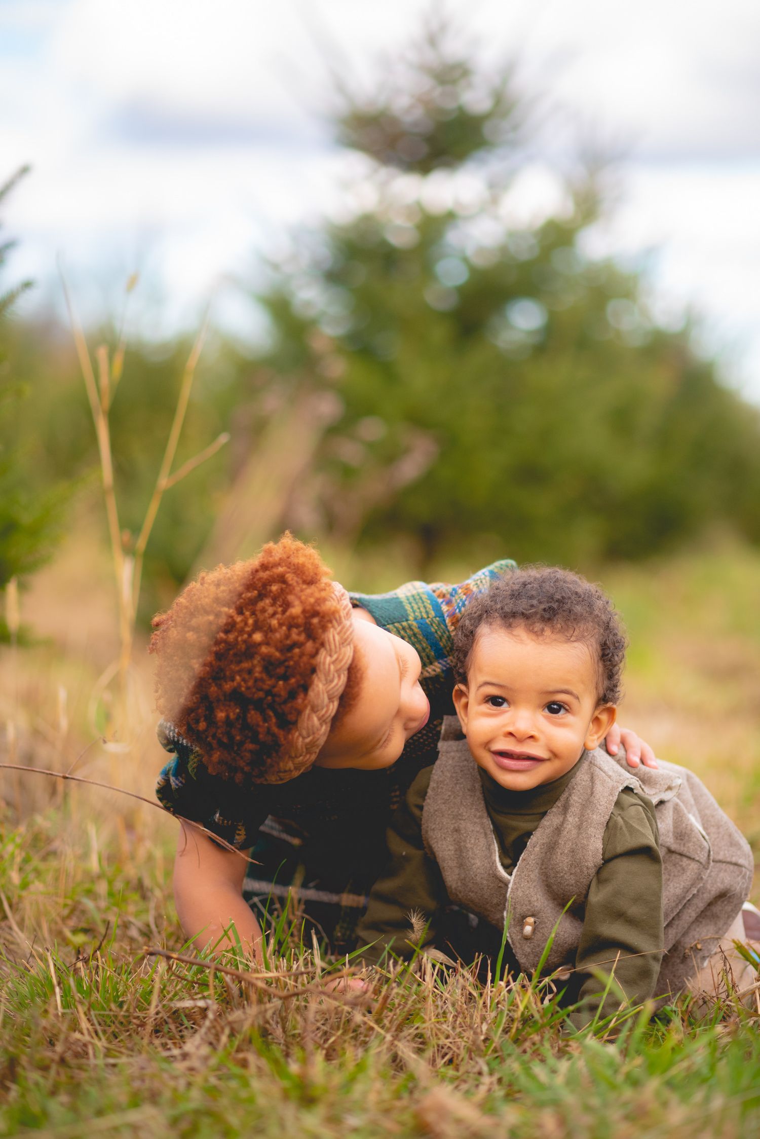 Two children playing in tall grass during an outdoor photoshoot.