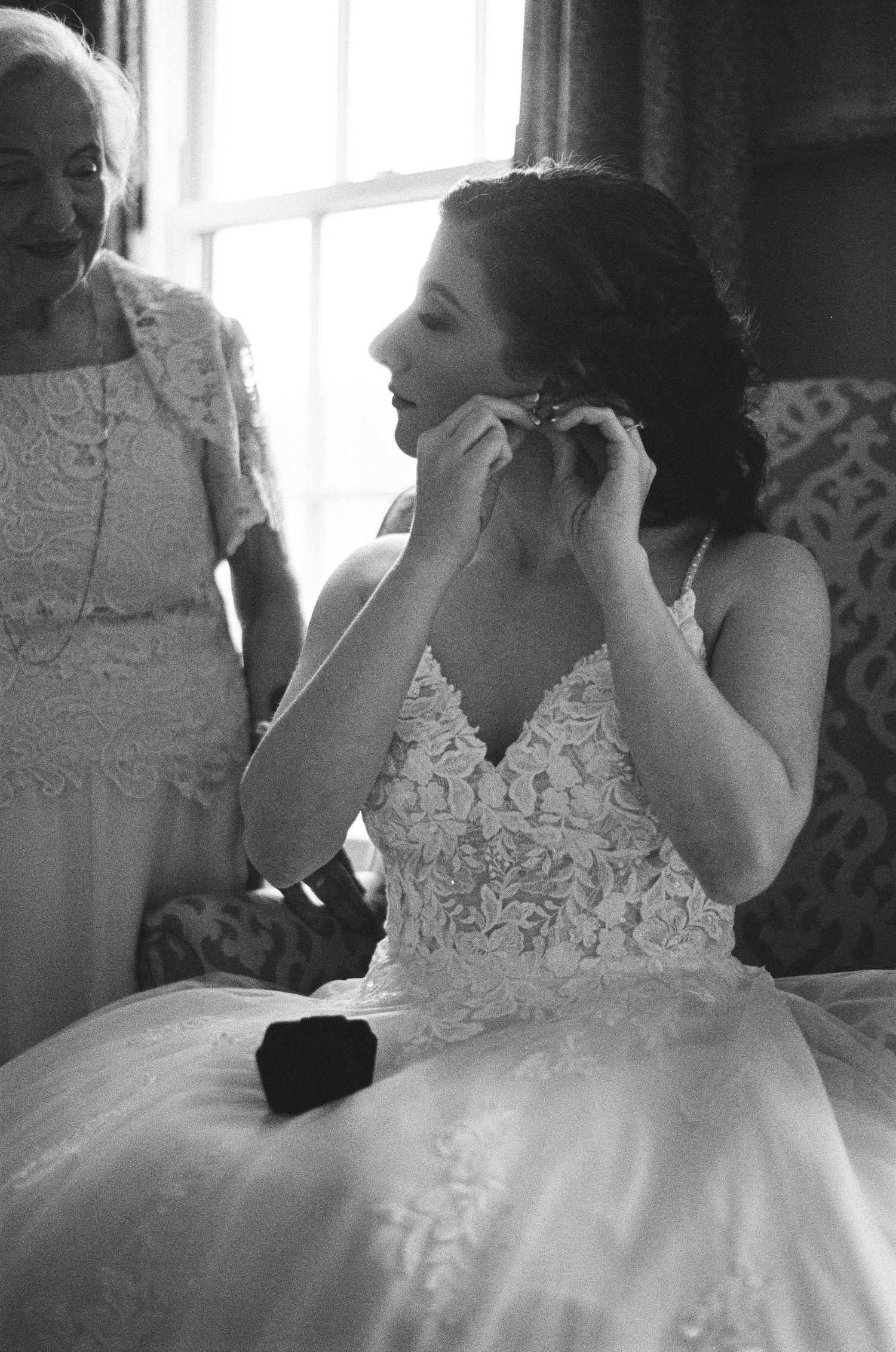 Black and white photo of wedding preparations with lace dress details.