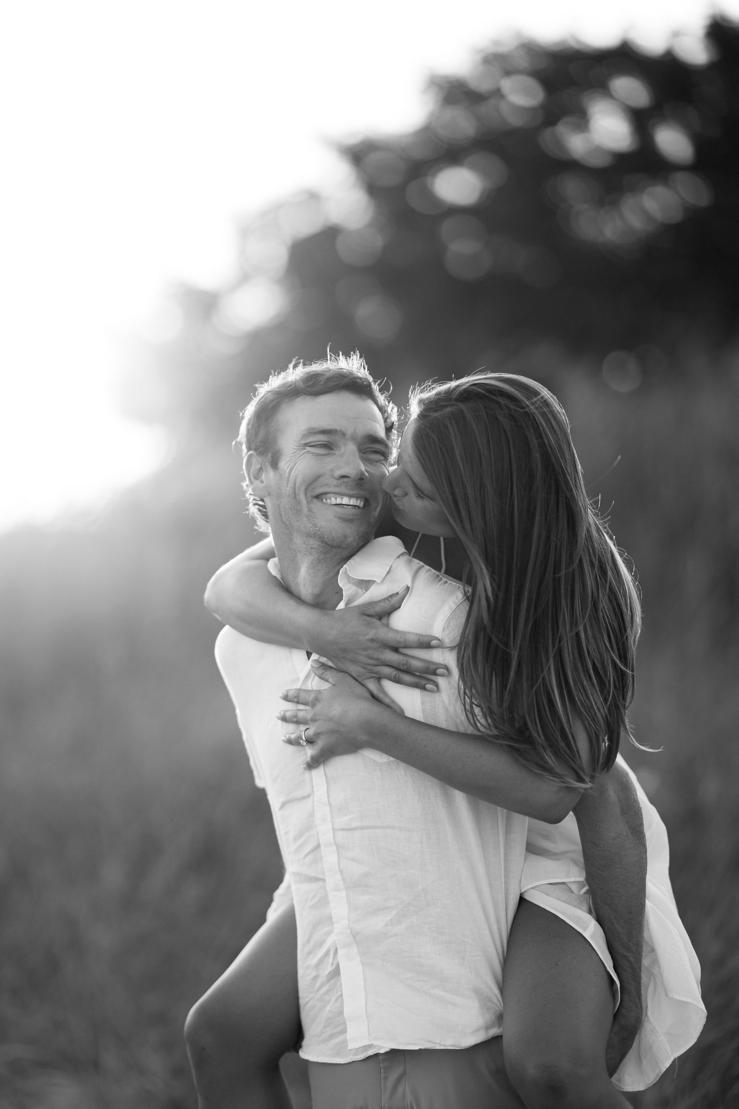 Black and white photo sequence of a romantic couple embracing and laughing together in natural outdoor lighting.