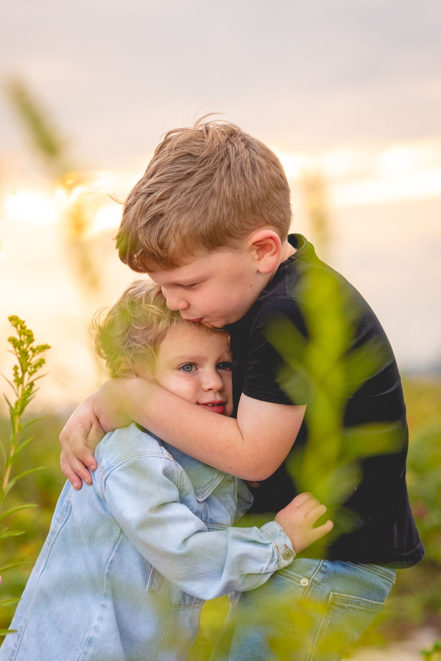 Two children sharing tender embrace in field during sunset.