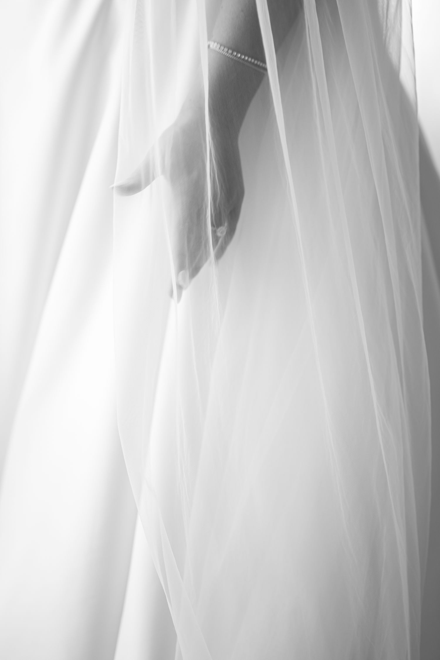 Close-up detail of flowing white wedding dress veil with soft ethereal lighting.