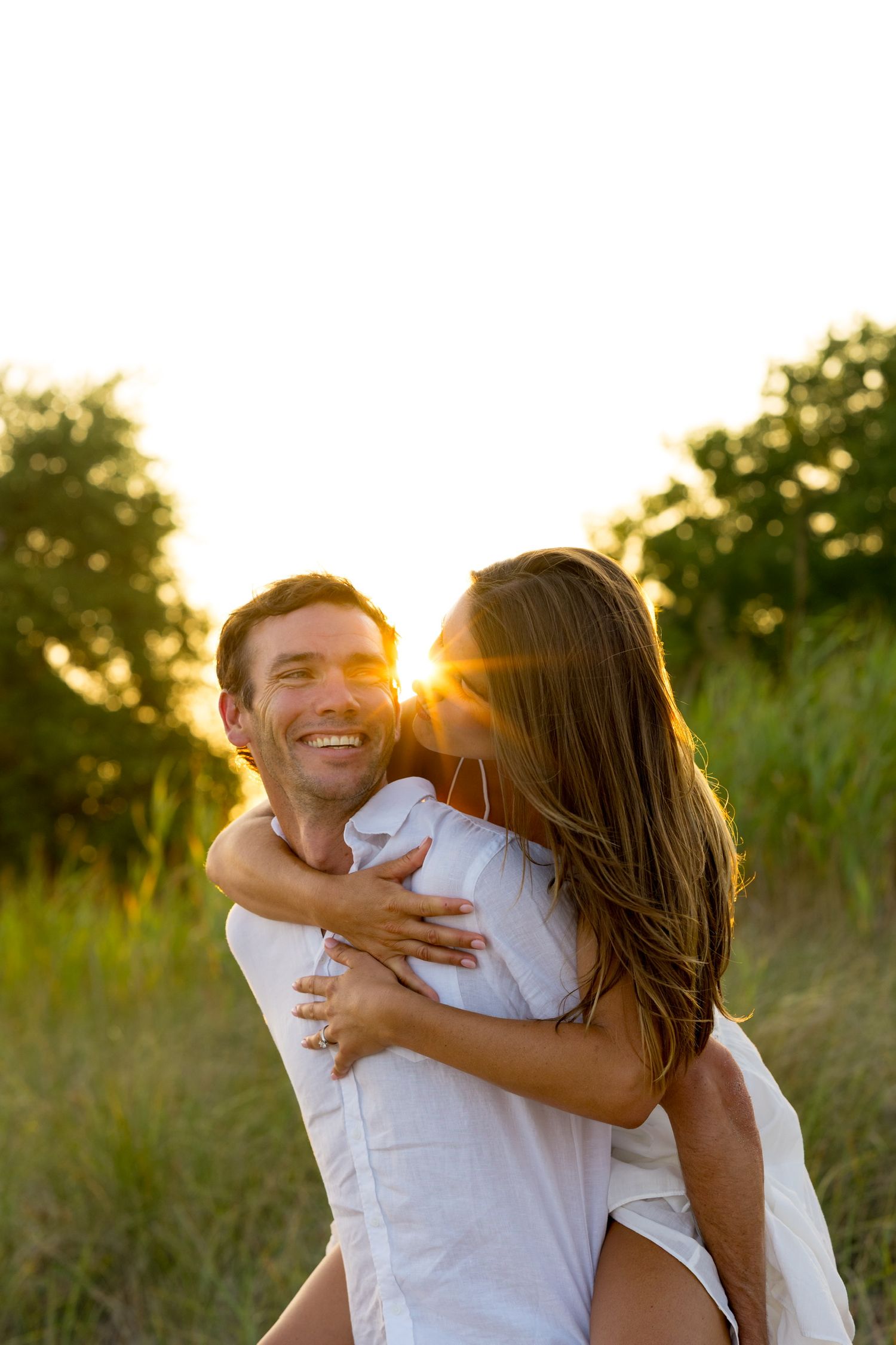 Couple embracing and laughing during golden hour photoshoot in a field in Westport, Connecticut.