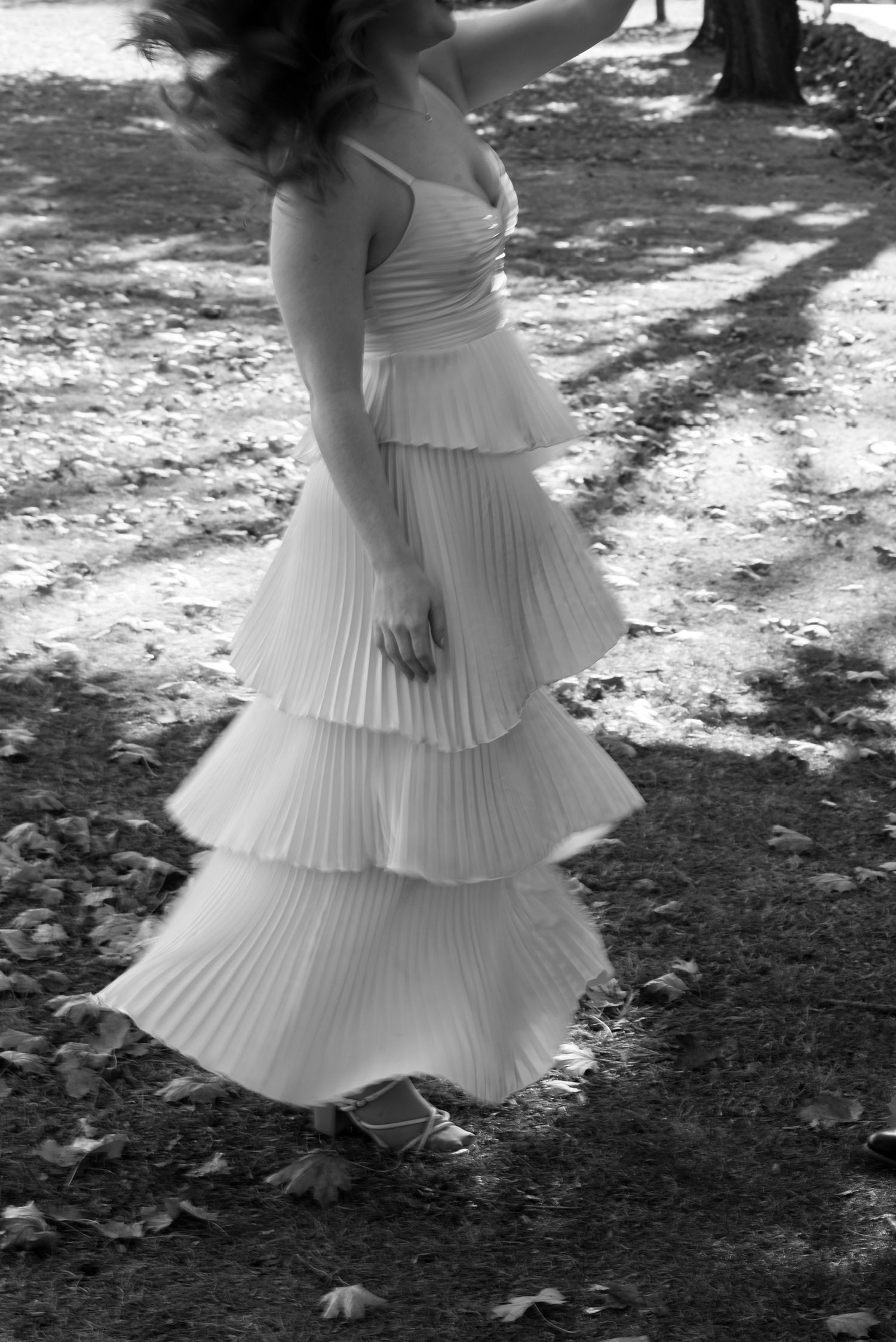 Black and white series showing movement of pleated white dress in outdoor setting.