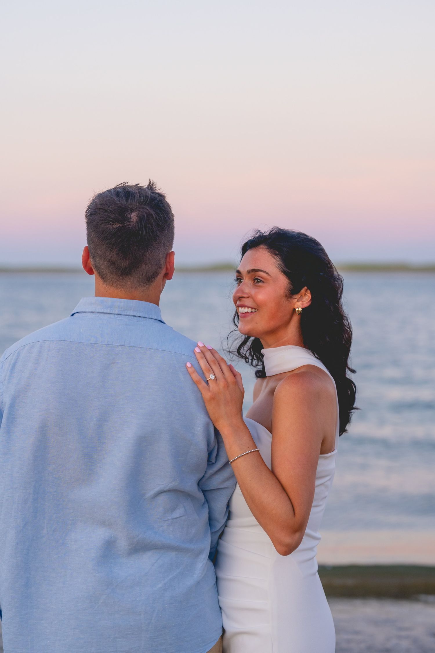 A couple shares joyful moments at sunset by the ocean.