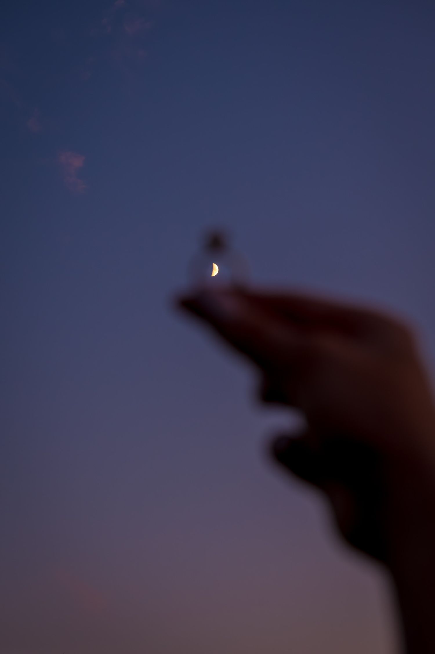 Crescent moon glowing in a deep blue twilight sky.