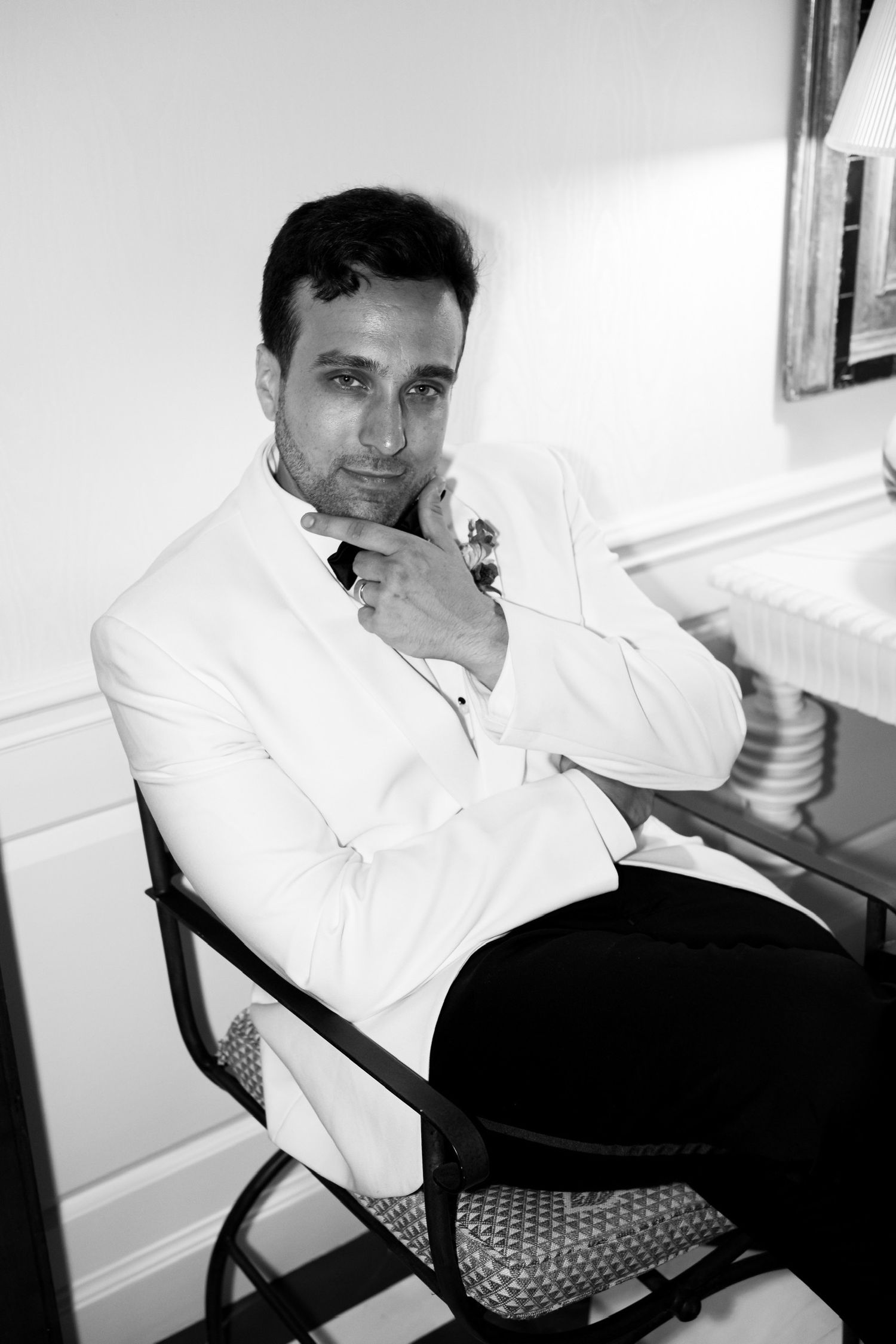 Black and white portrait of person in white formal attire seated in chair.