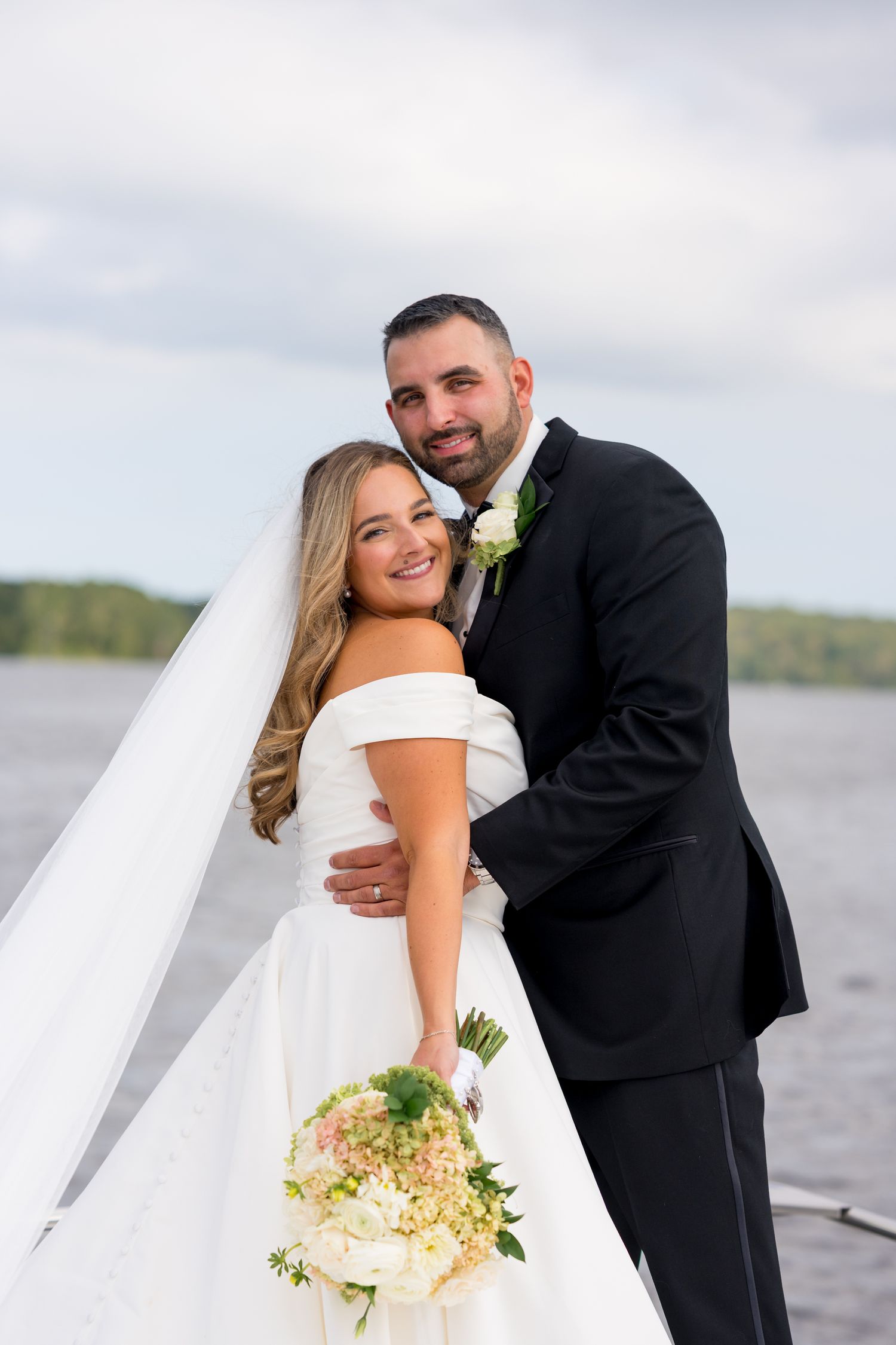 Romantic wedding photos of newlyweds posing together on a dock by a scenic lake.
