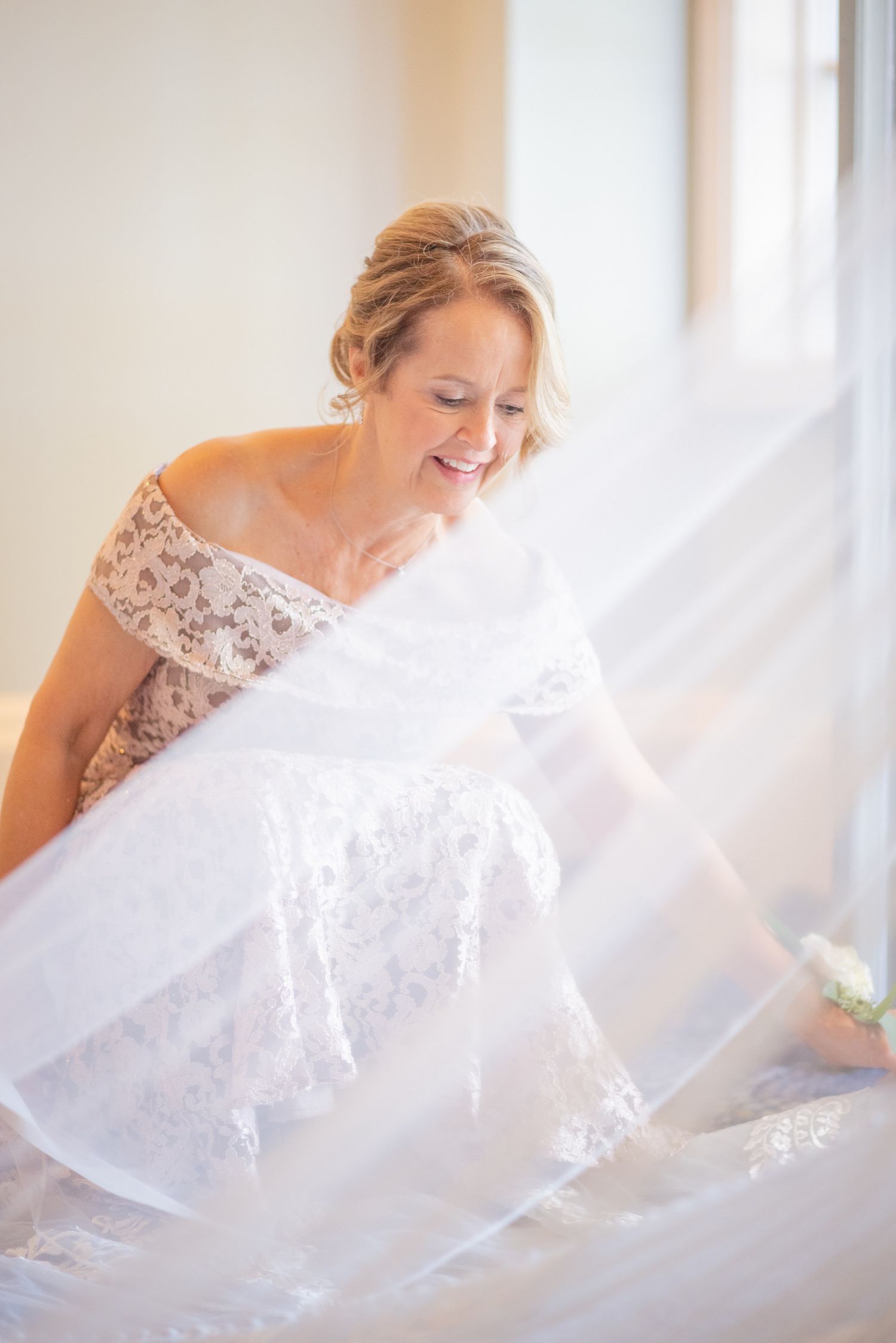 A flowing white lace wedding veil captured in soft, ethereal indoor lighting.