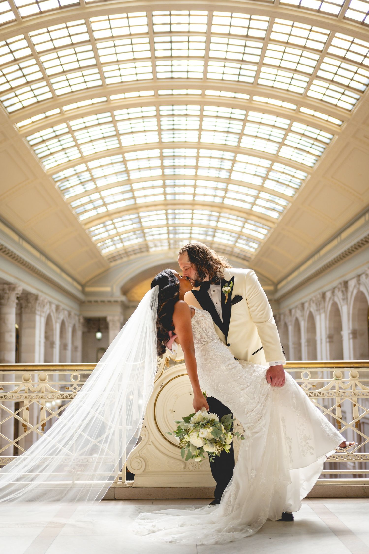 Flowing wedding dress train captured in elegant architectural setting with skylight ceiling.