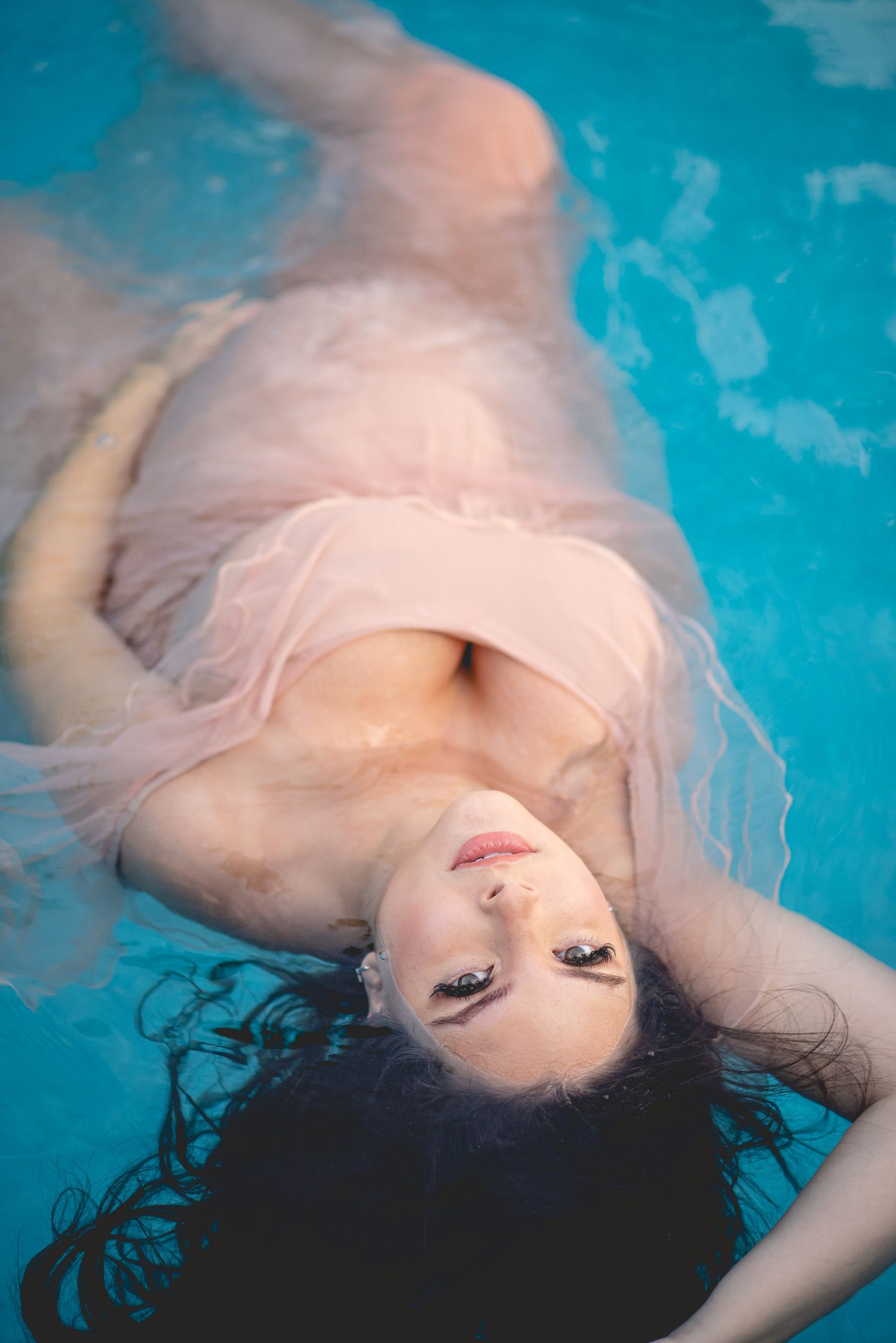 Artistic underwater photography with flowing fabric in a blue pool.