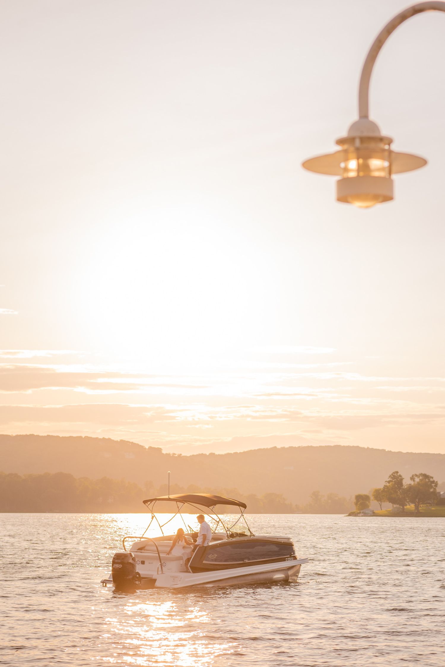 Scenic sunset view of boats on calm lake waters with mountains in background.