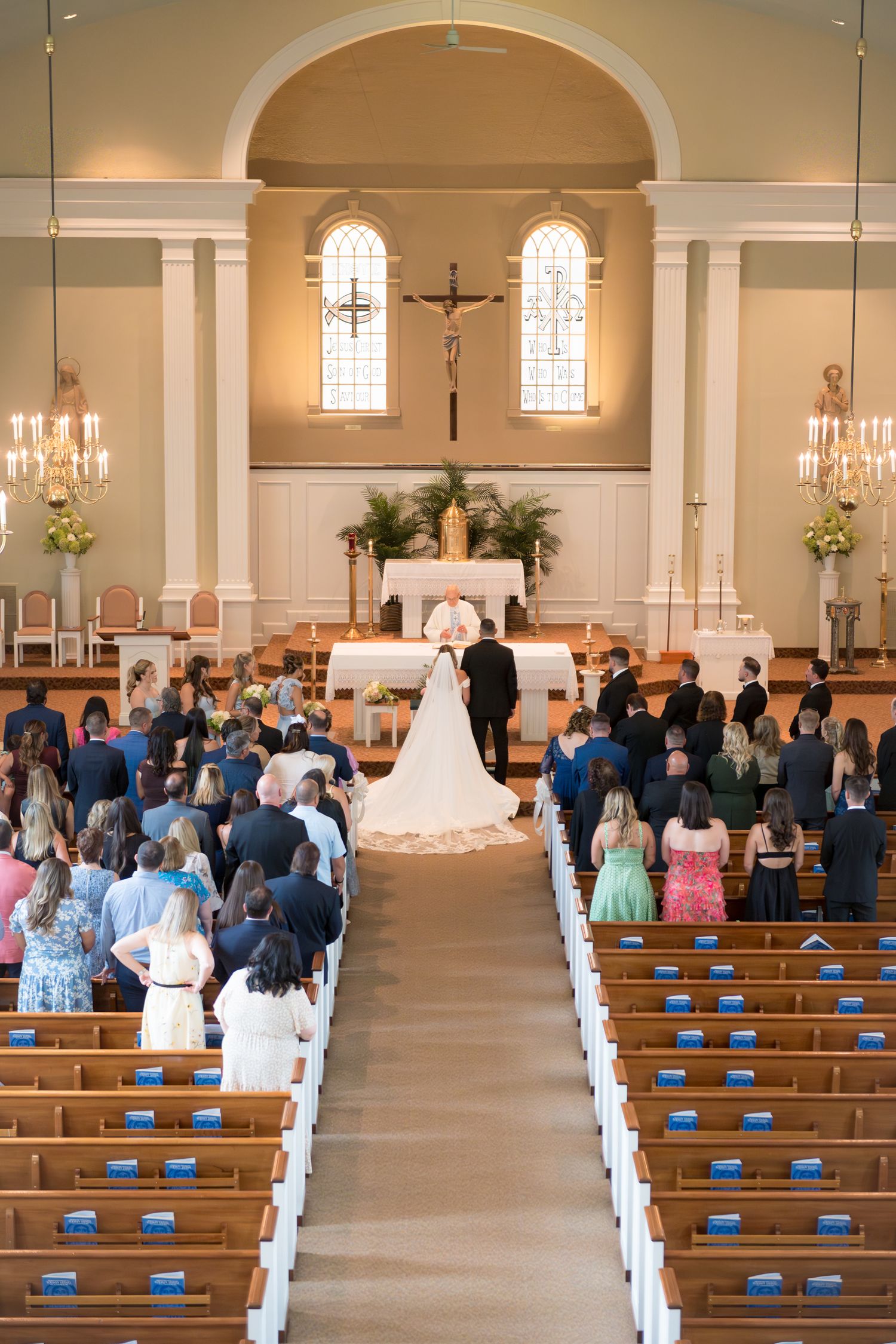 Wide view of a church sanctuary filled with guests seated in wooden pews during a wedding ceremony.
