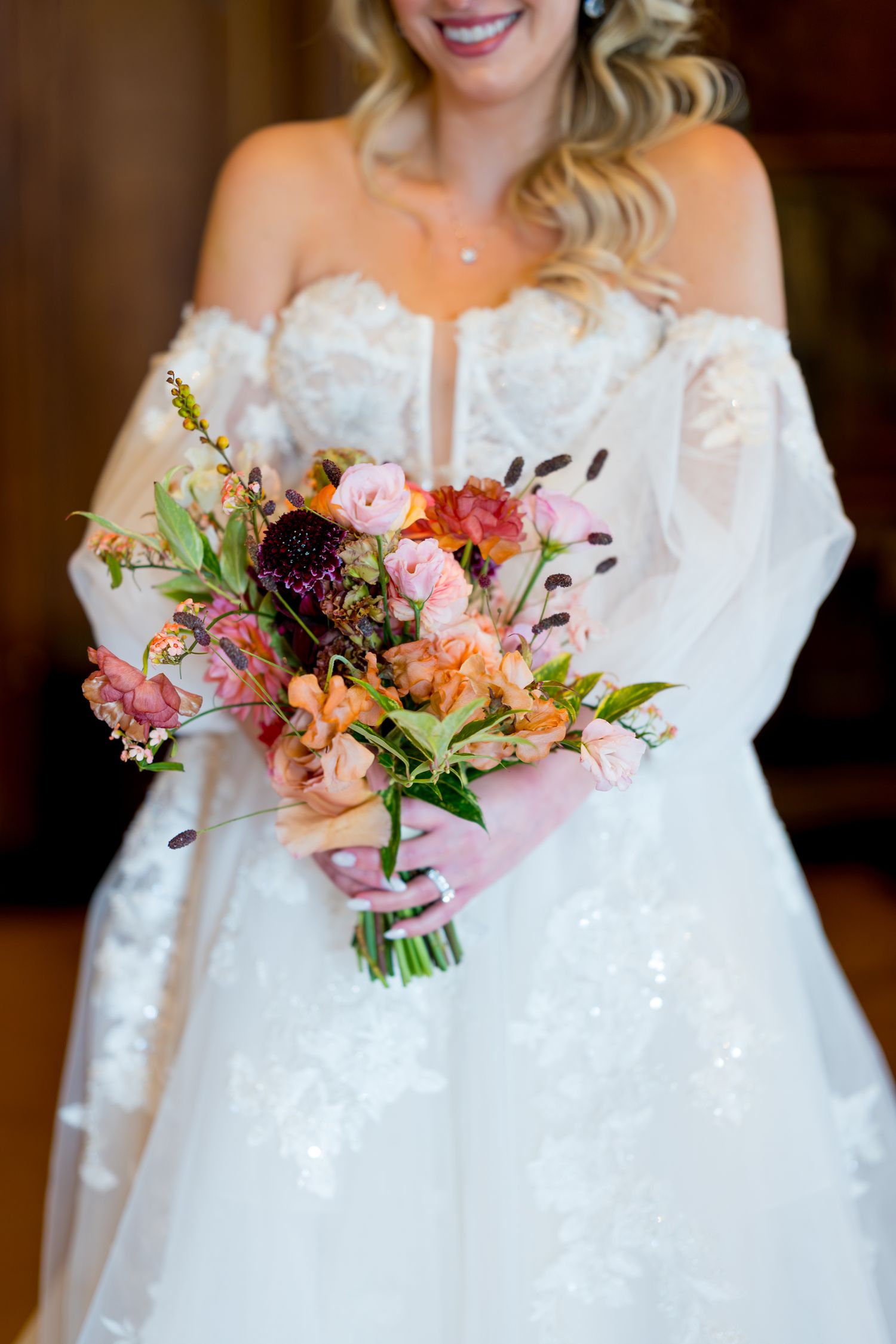Wedding bouquets featuring coral and pink flowers with off-shoulder white bridal gowns.