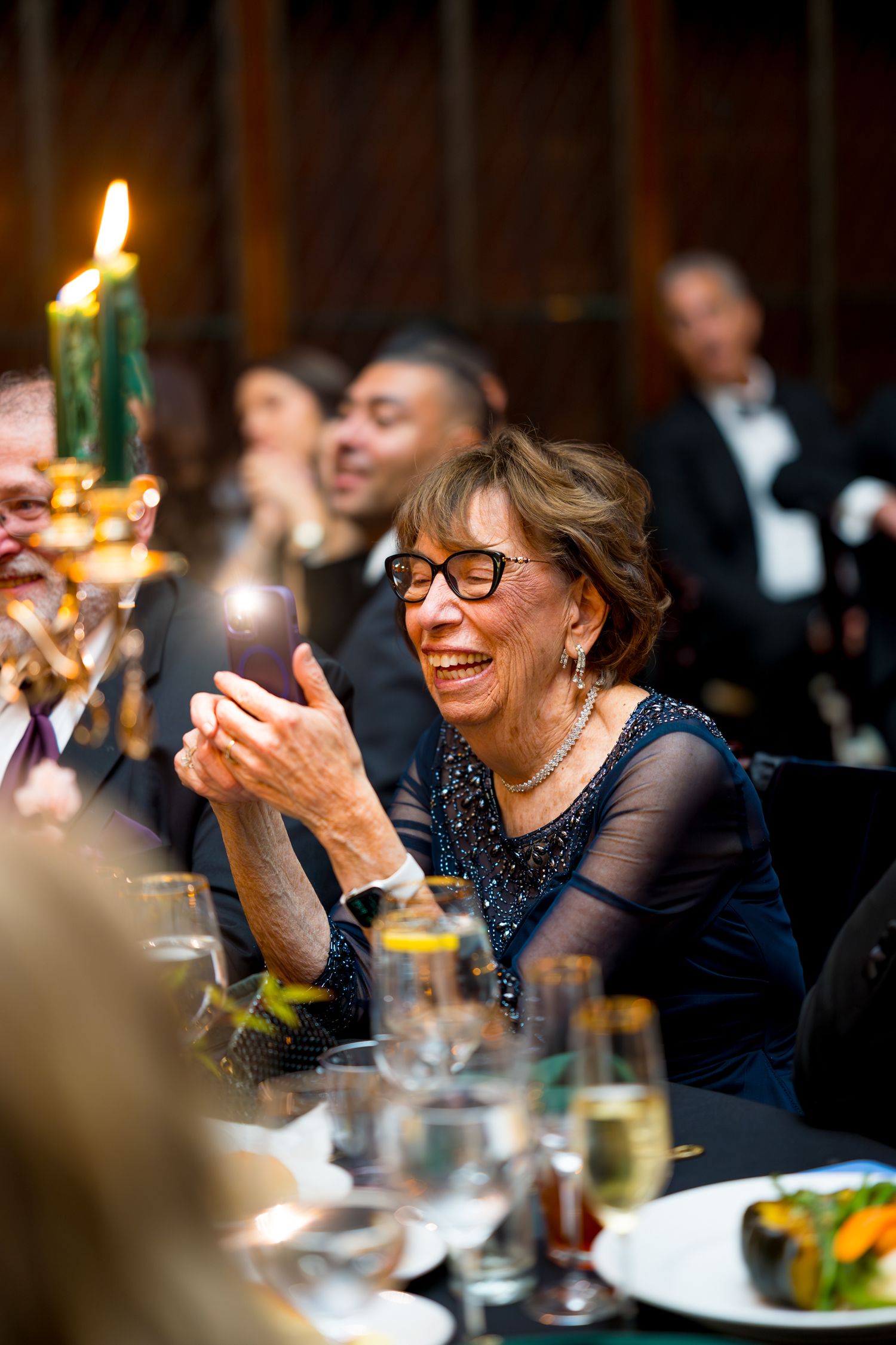 Guests at an elegant dinner party enjoy a candlelit celebration with warm smiles and glowing ambiance.
