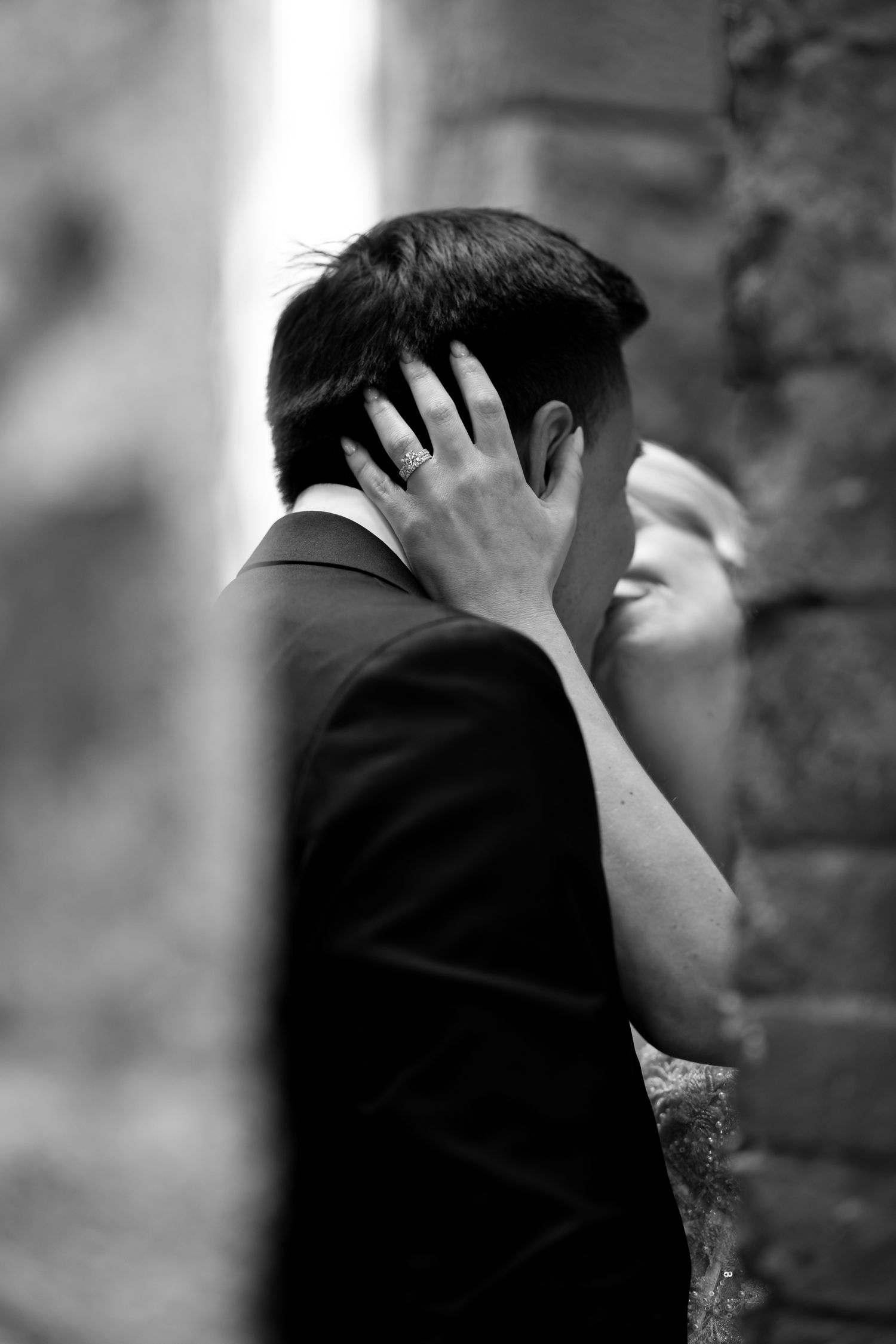 A romantic black and white wedding photo showing a tender moment between a couple in formal attire.