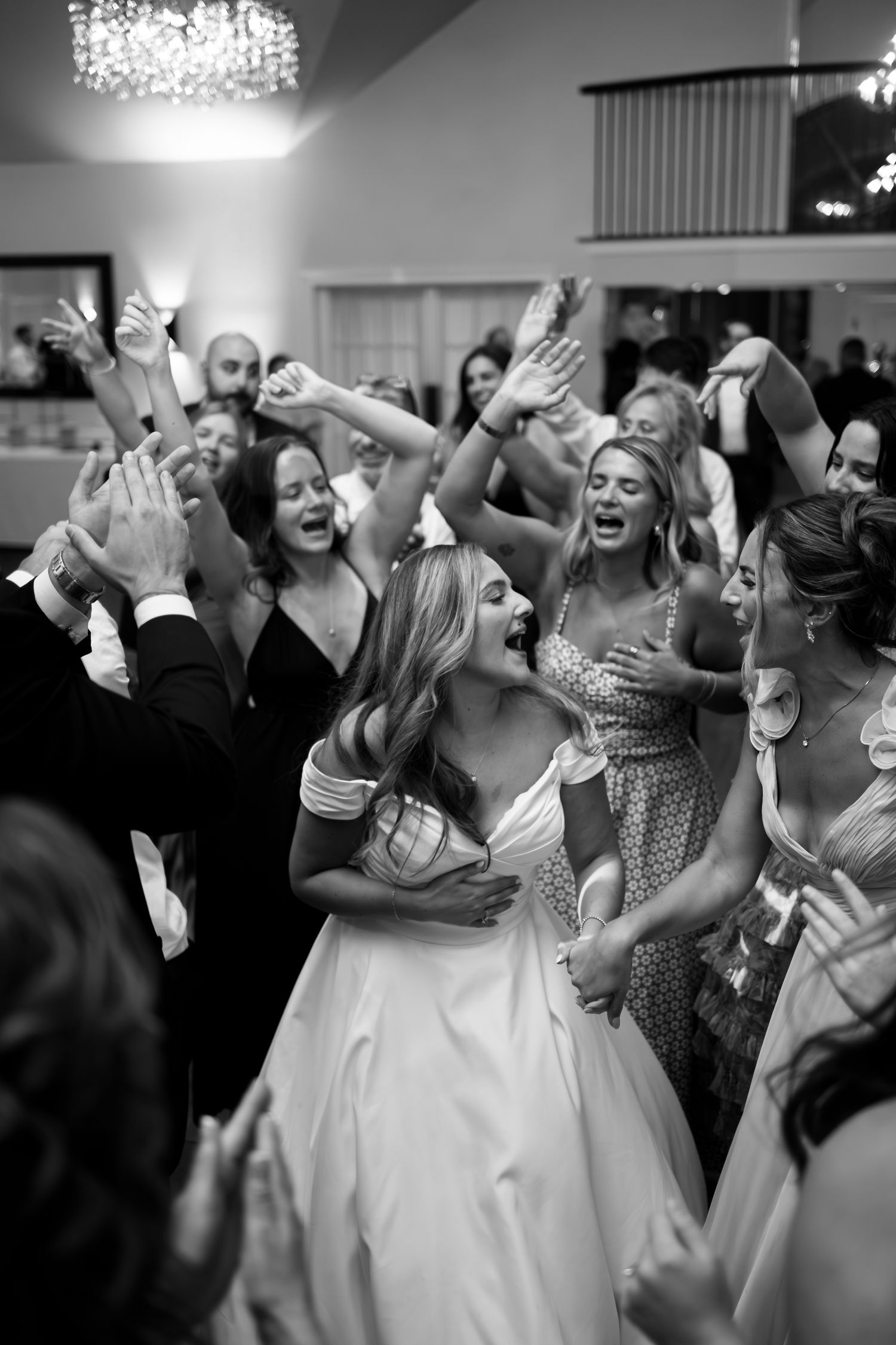 Wedding reception dance floor filled with joyful celebration and raised hands.